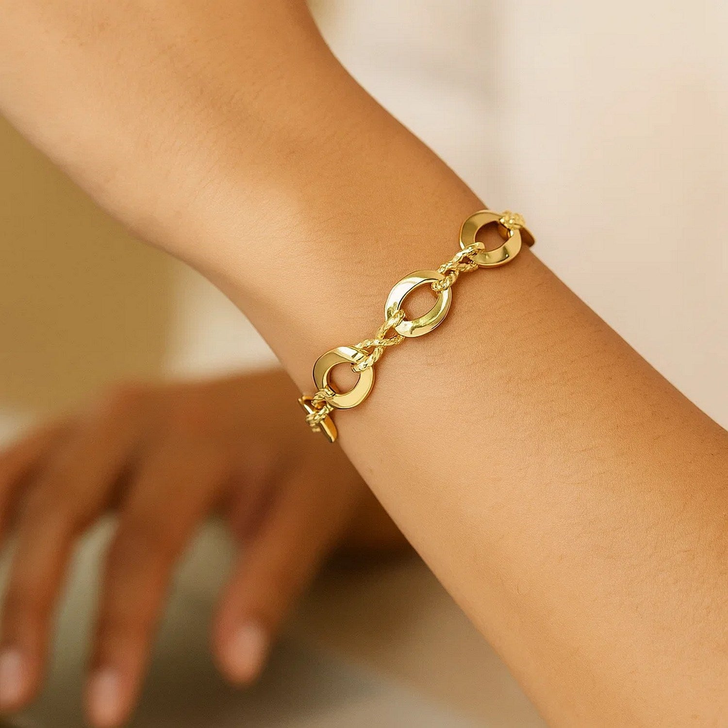 14k yellow gold infinity link bracelet on a person's wrist.