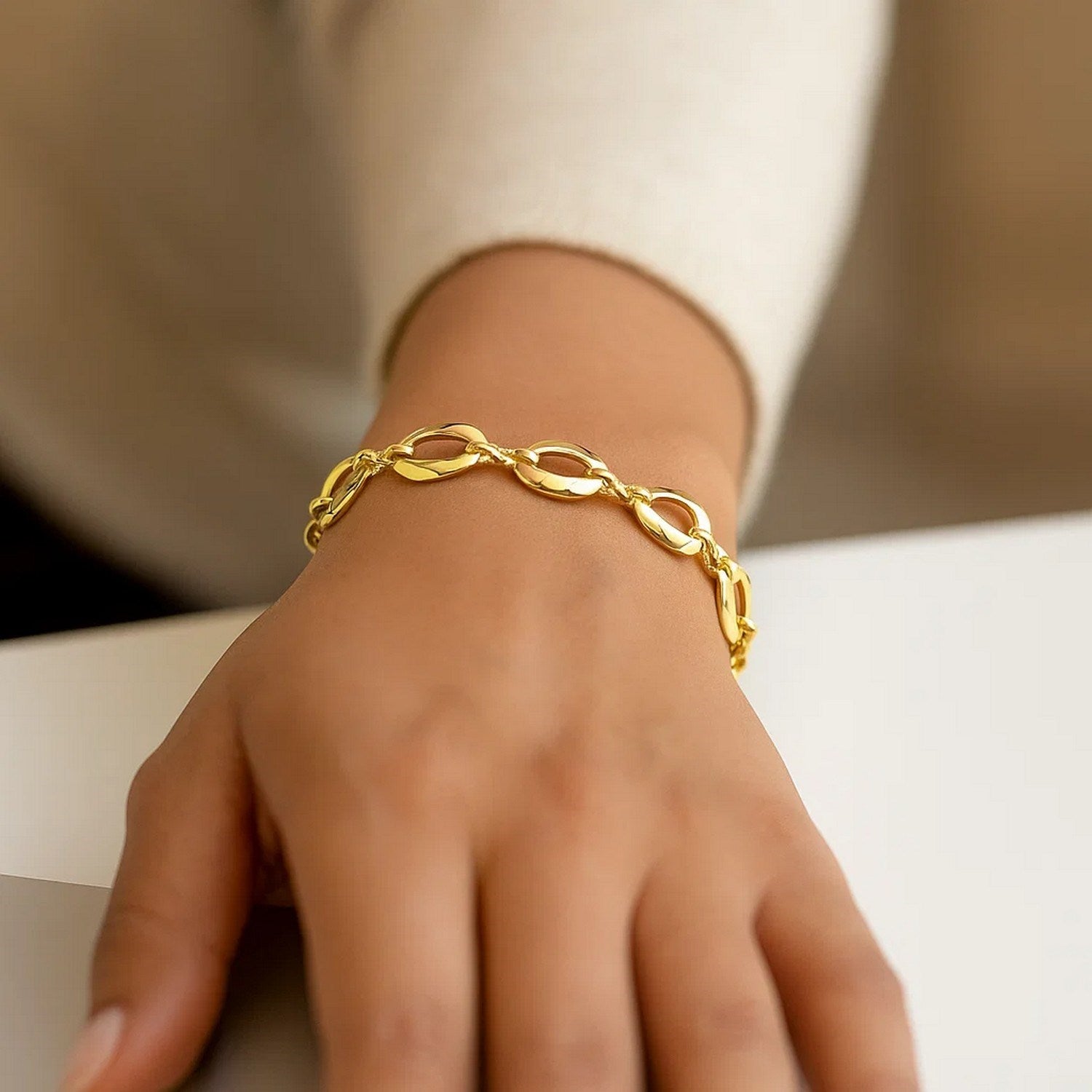 14k yellow gold infinity link bracelet on a person's wrist.
