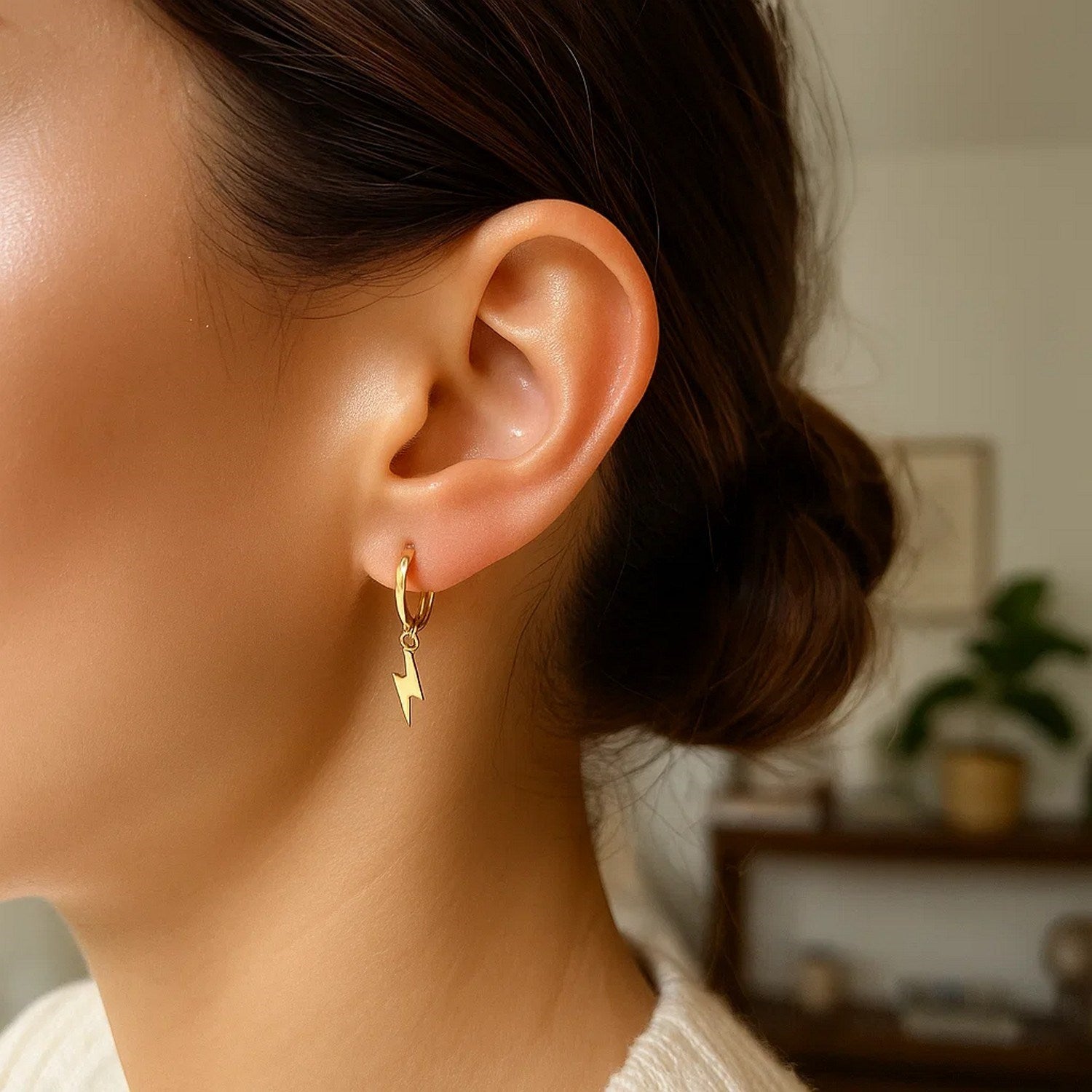 14K yellow gold lightning bolt drop hoop earring on a woman's ear.