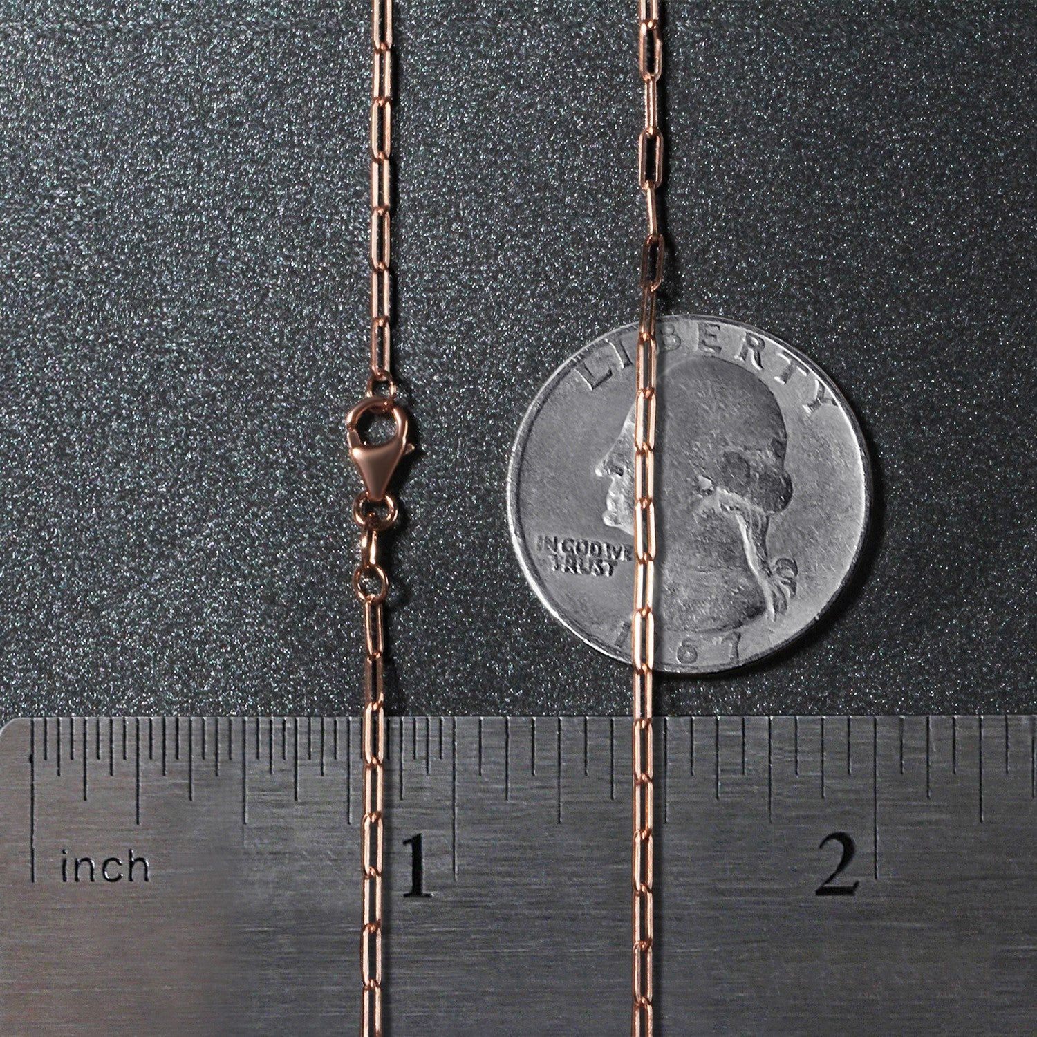 A 14K rose gold paperclip chain with a lobster clasp is shown next to a ruler and coin.