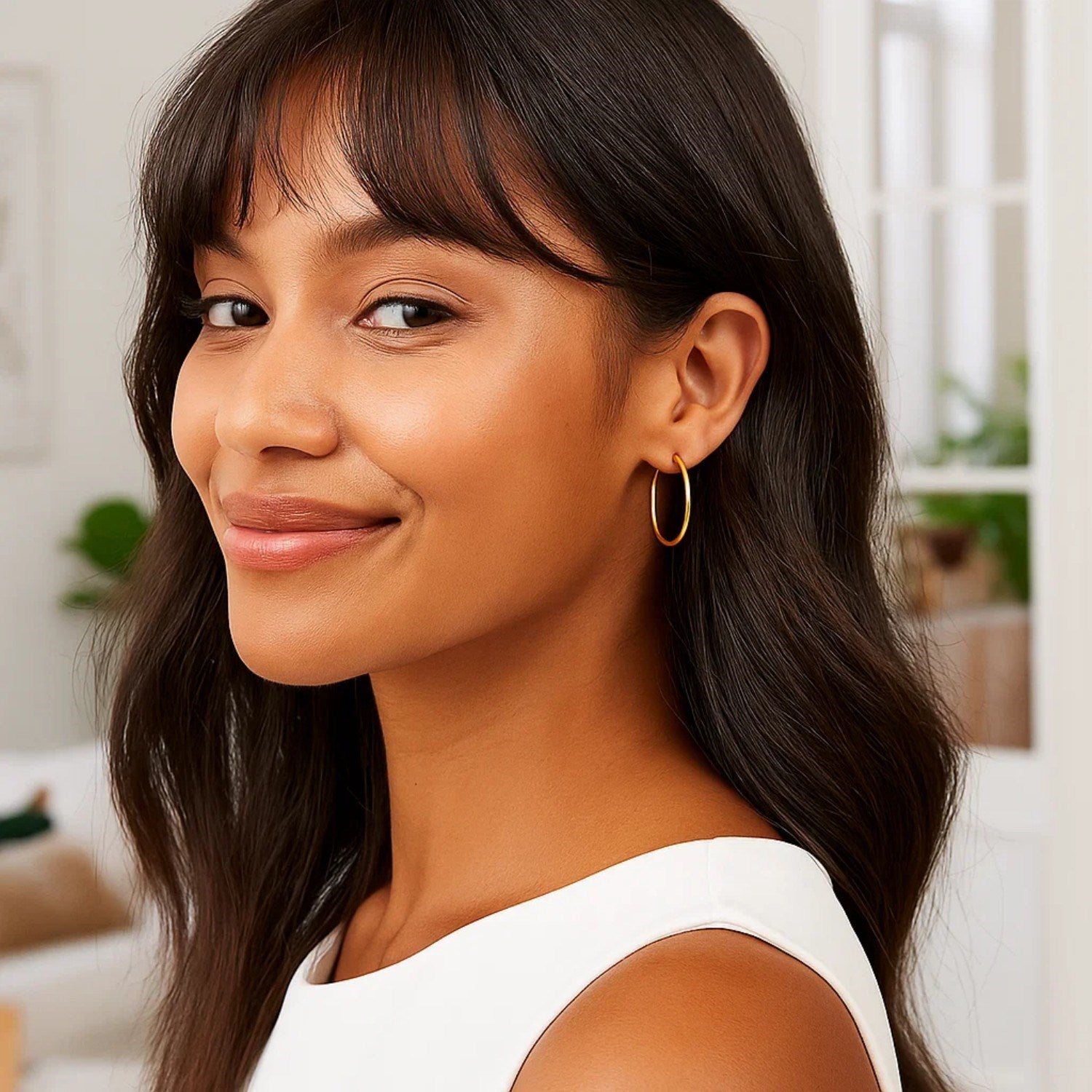 A woman wears 10k yellow gold polished hoop earrings.
