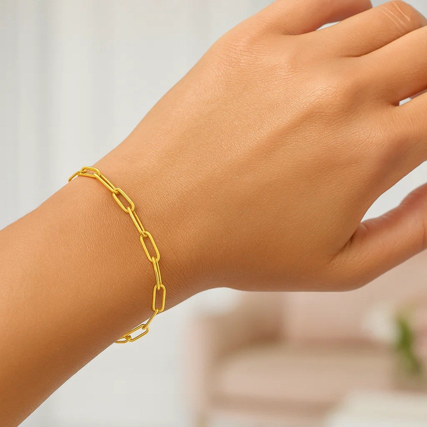 14K yellow gold paperclip bracelet with 3.5mm wide links on a person's wrist.