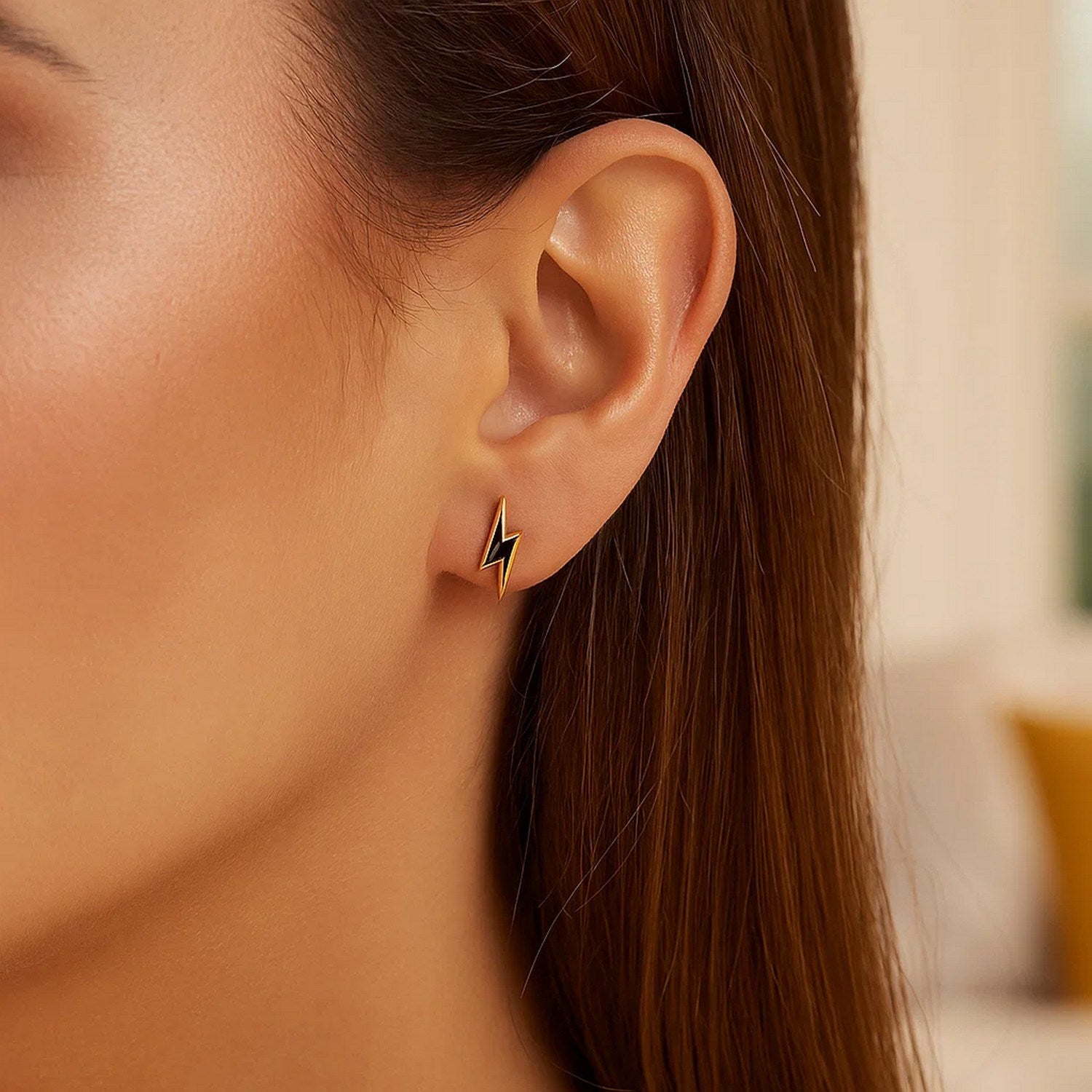 14k yellow gold and enamel black lightning bolt stud earring on a woman's ear.
