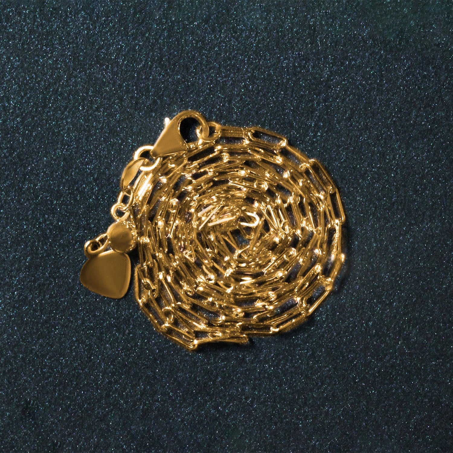 A 14k yellow gold adjustable paperclip chain with a heart dangle and lobster clasp.