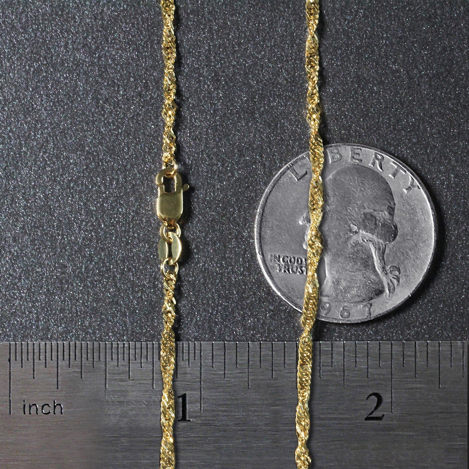 A 14k yellow gold Singapore chain with a lobster clasp, shown with a ruler and coin for scale.