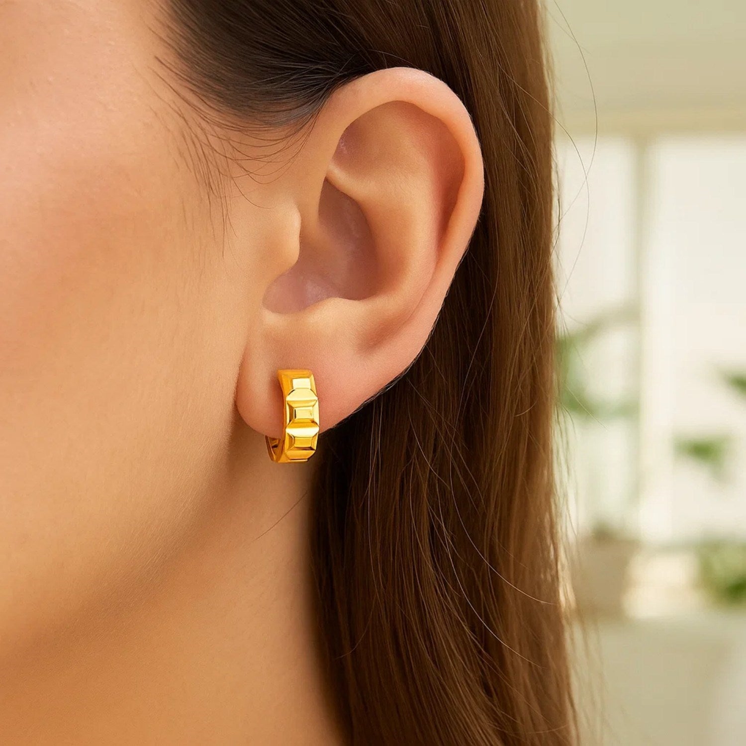 14K yellow gold J hoop earrings with a square faceted surface on a woman's ear.
