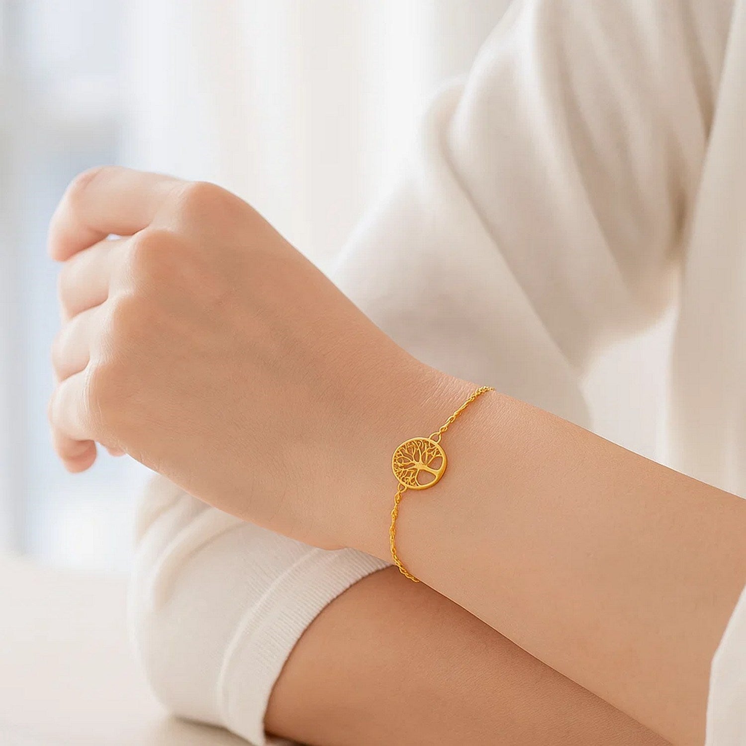 14K yellow gold Tree of Life bracelet on a person's wrist.
