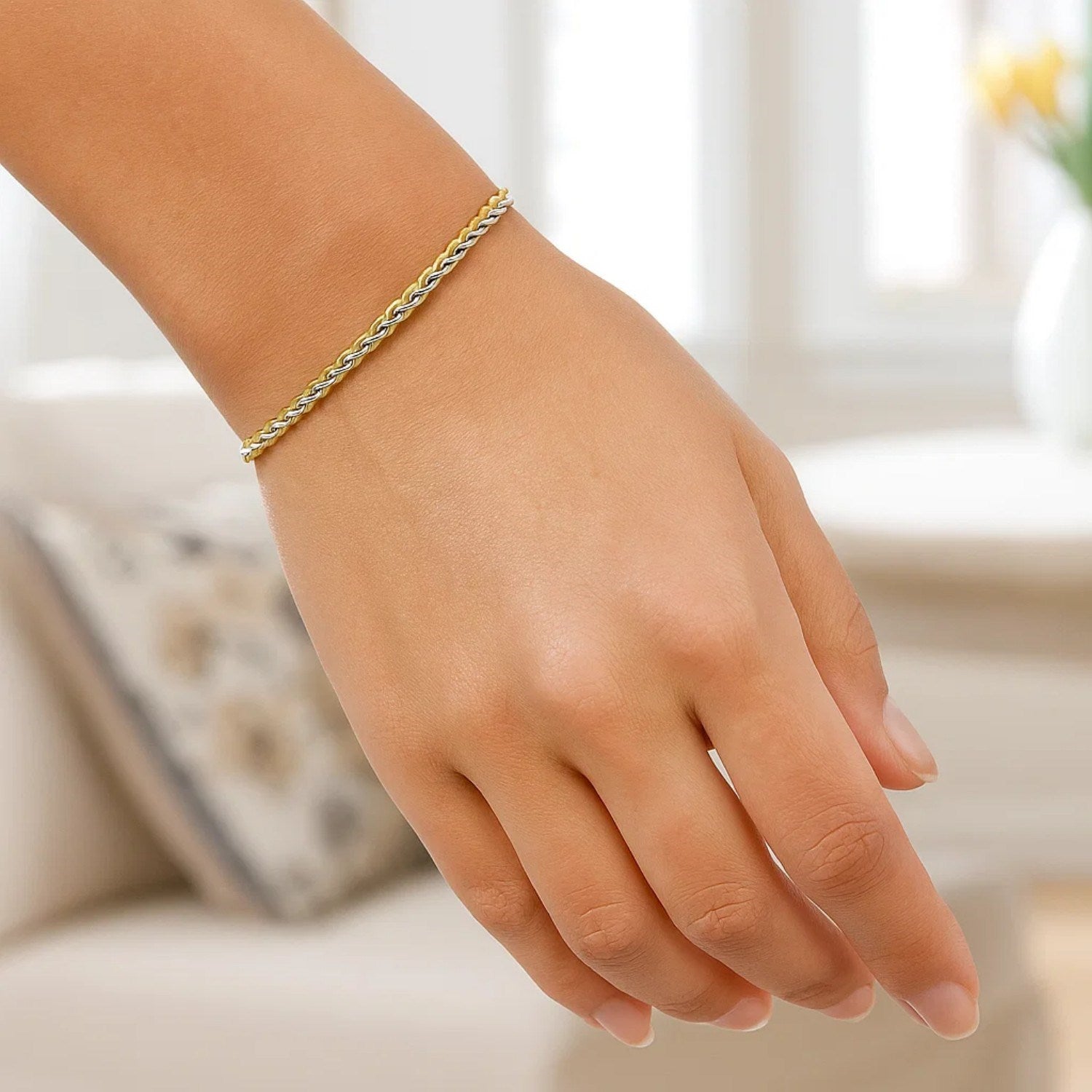 A two-toned wheat chain bracelet in yellow and white gold on a person's wrist.