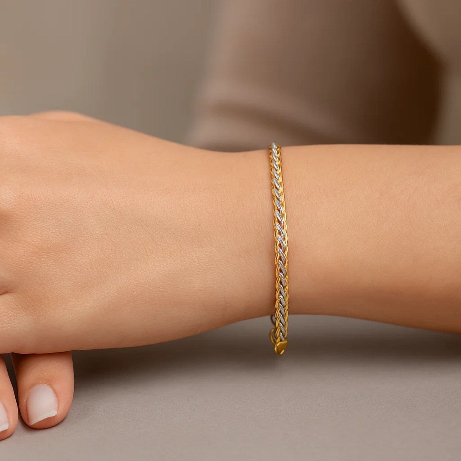 Two-toned wheat chain bracelet in 10k yellow and white gold on a wrist.
