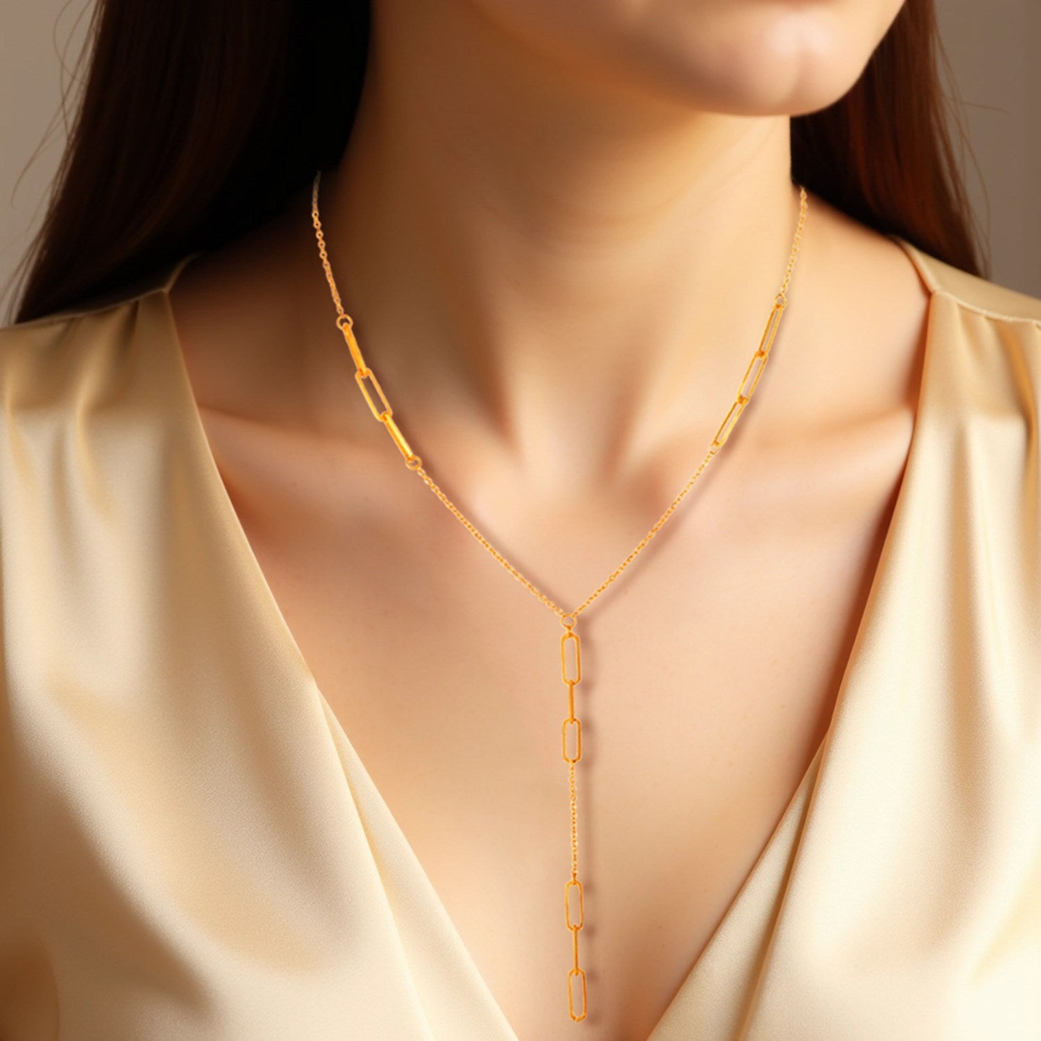 14K yellow gold lariat necklace with paperclip chain stations on a woman's neck.
