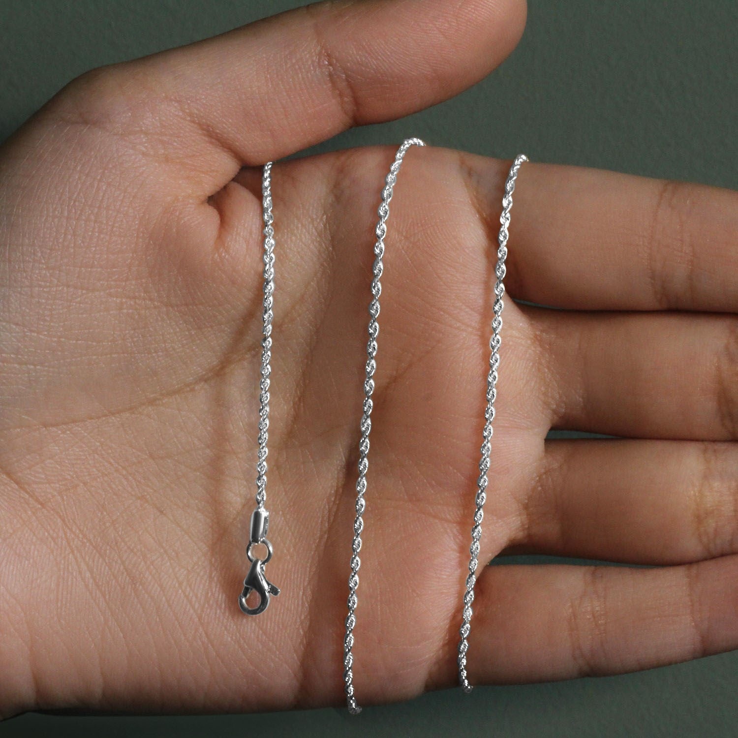 10k white gold solid diamond cut rope chain with a lobster clasp, held in a hand.