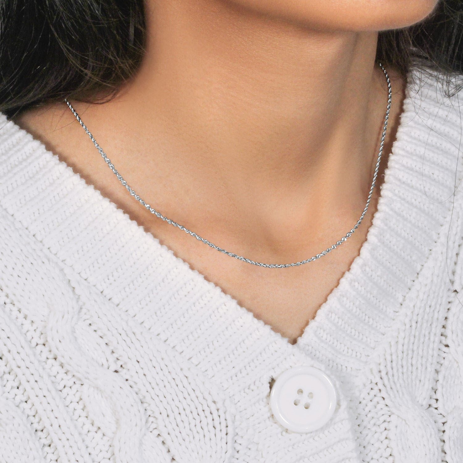 A white gold diamond-cut rope chain is worn around a person's neck.