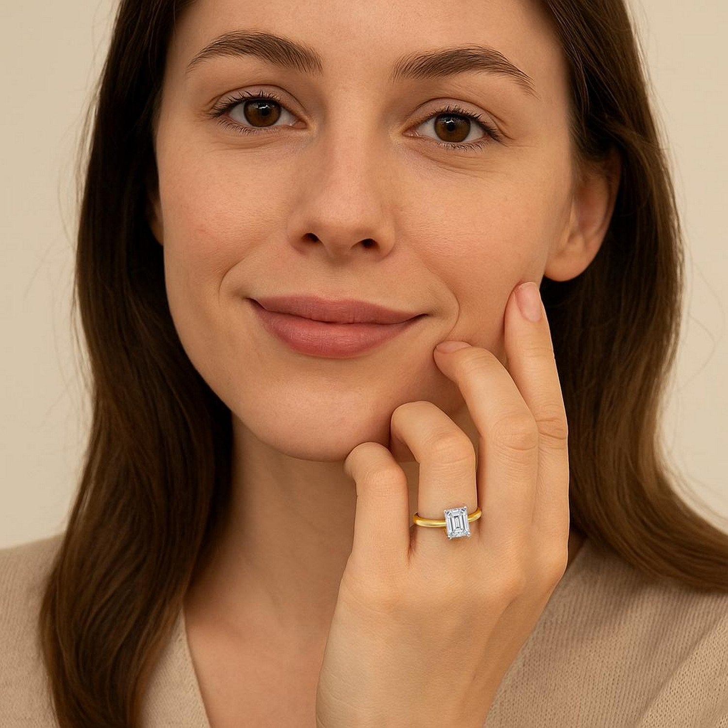 A woman wears a 1.50 carat emerald lab grown diamond ring in 14K yellow gold.