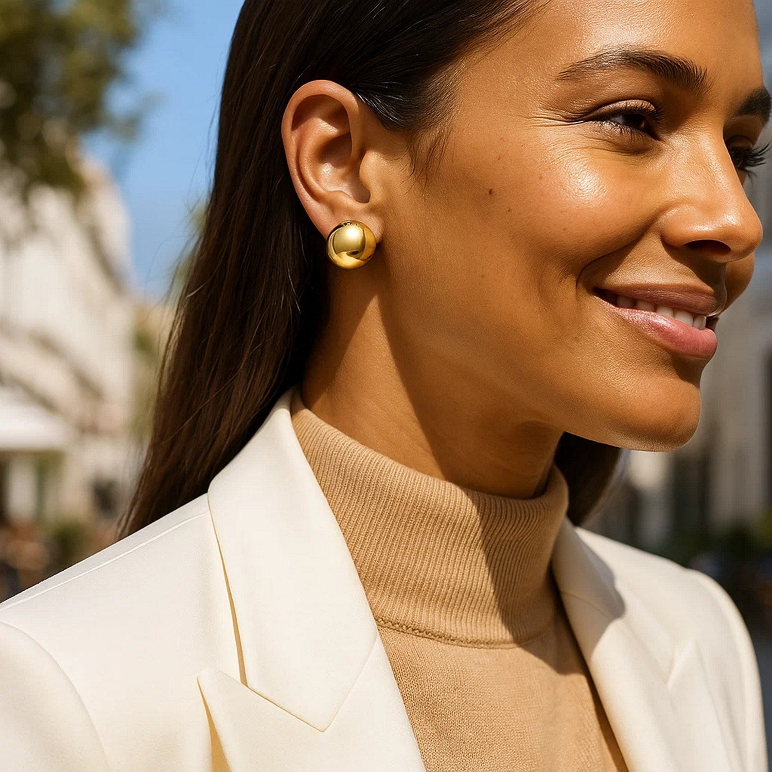 Puffed button stud earrings in 14K yellow gold on a woman's ear.