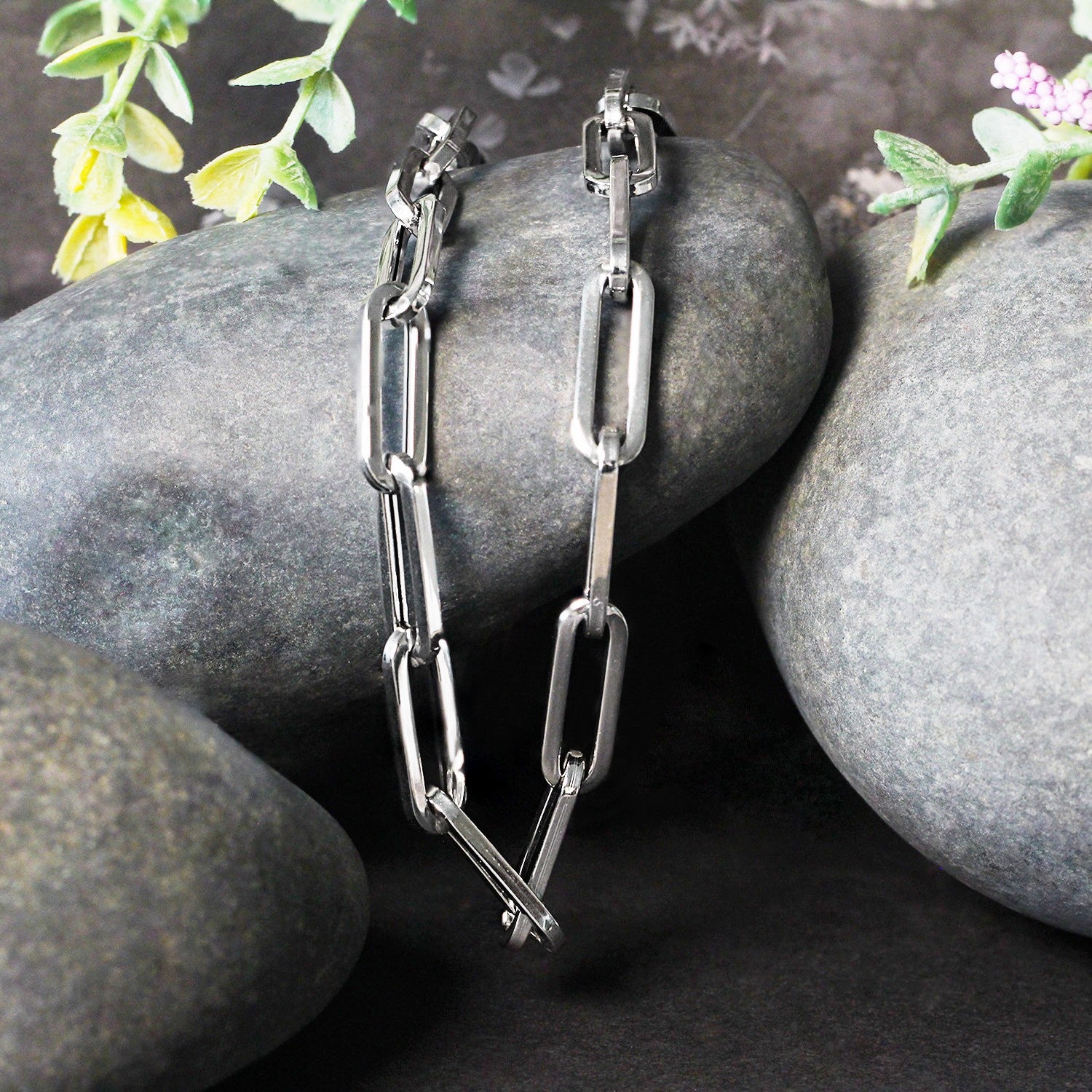 14K white gold wide paperclip chain with 6.10 mm links on gray stones.