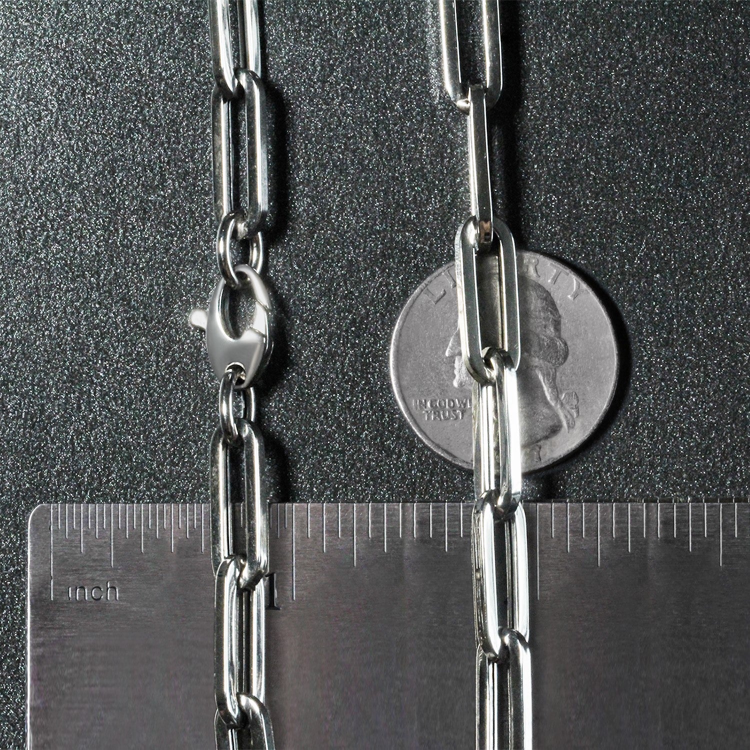 A 14K white gold wide paperclip chain with a lobster clasp, shown with a ruler and coin for scale.