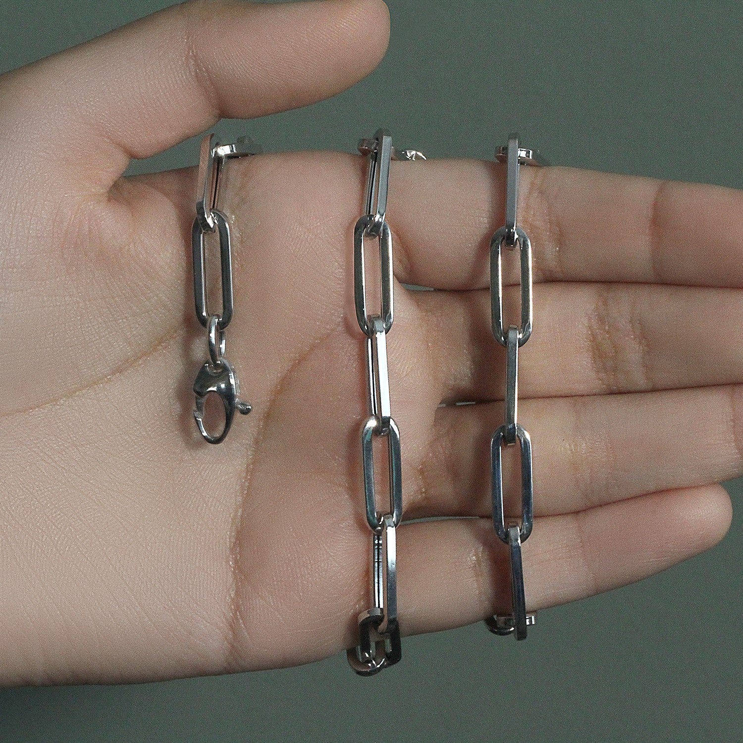 14K white gold wide paperclip chain with a lobster clasp on a hand.