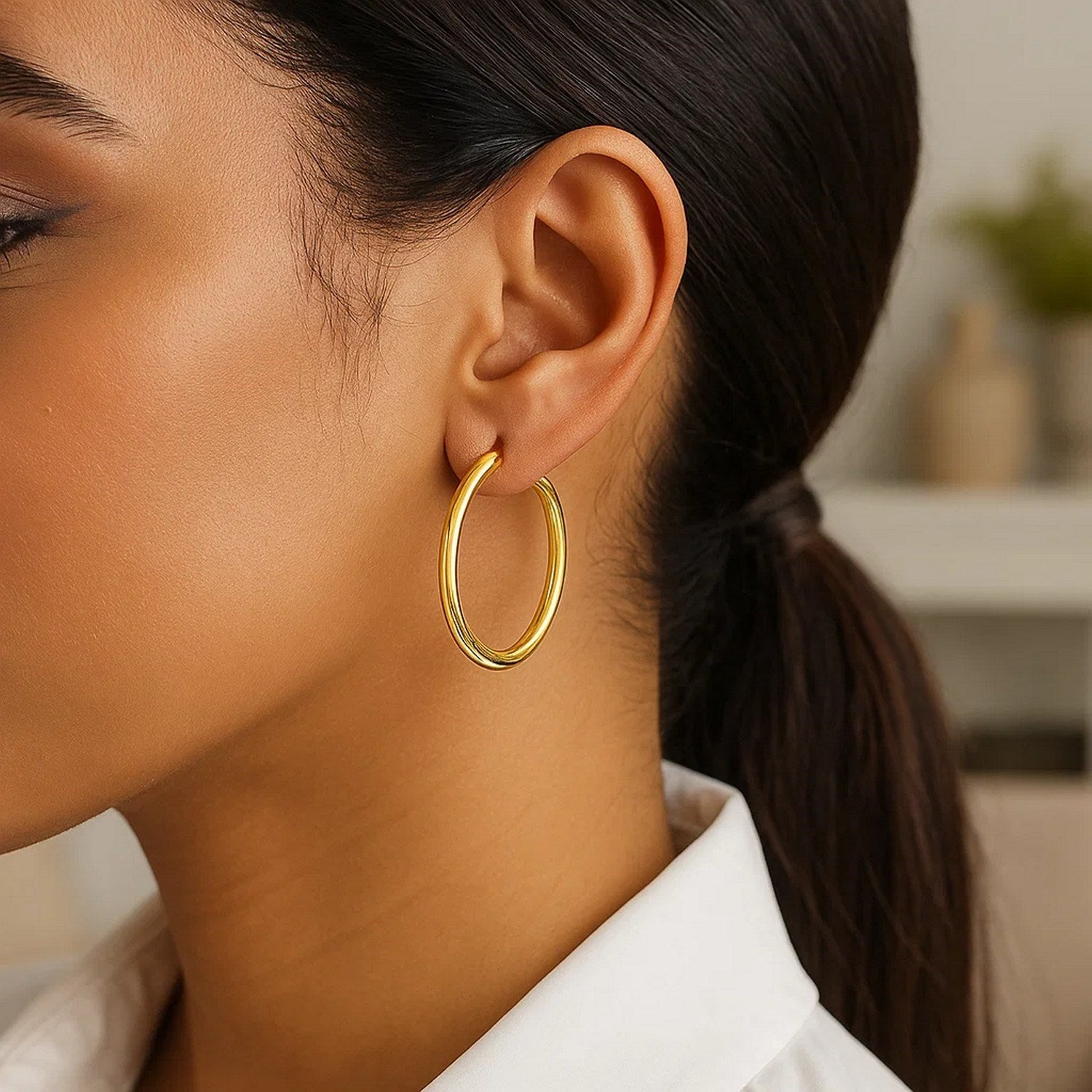 10k yellow gold polished hoop earrings on a person's ear.