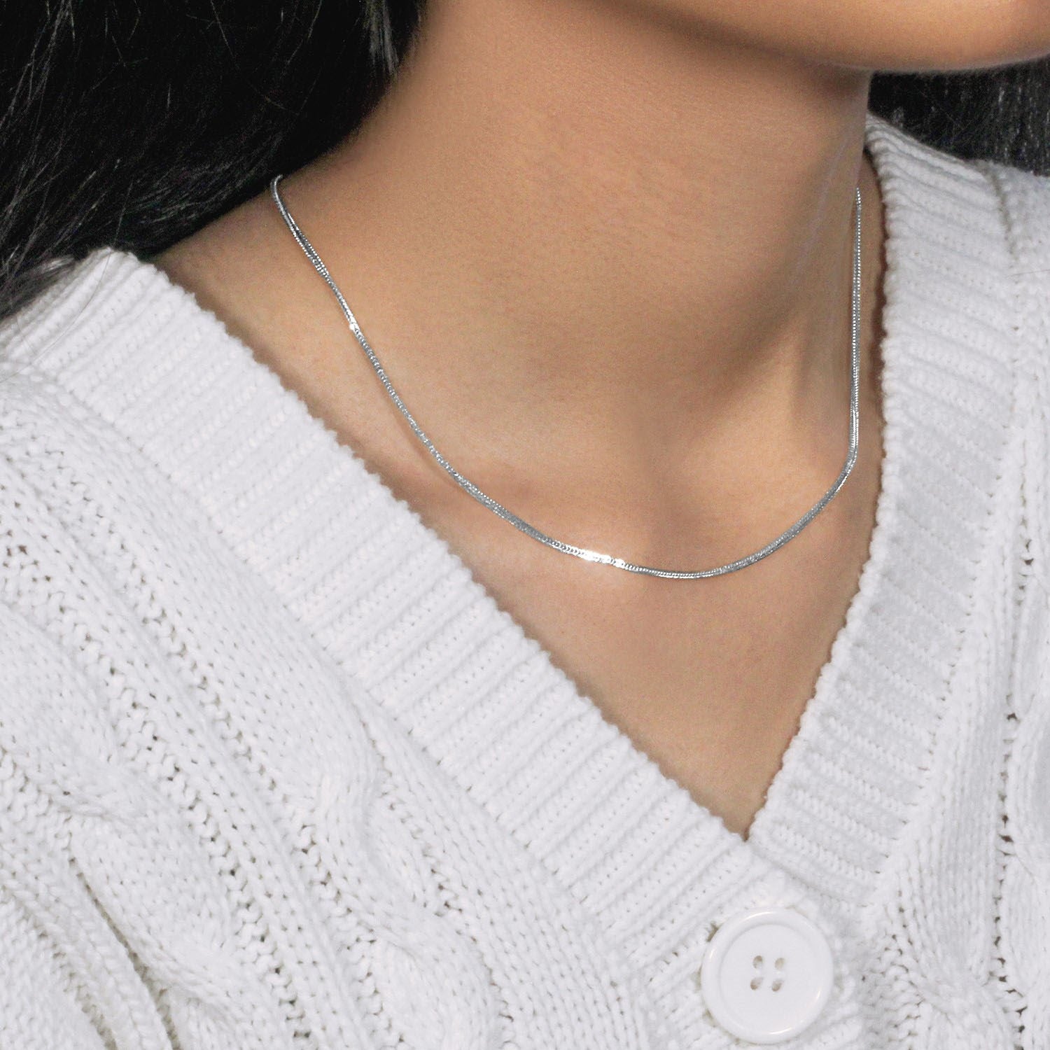 A 14k white gold foxtail chain with a lobster clasp worn by a person in a white sweater.