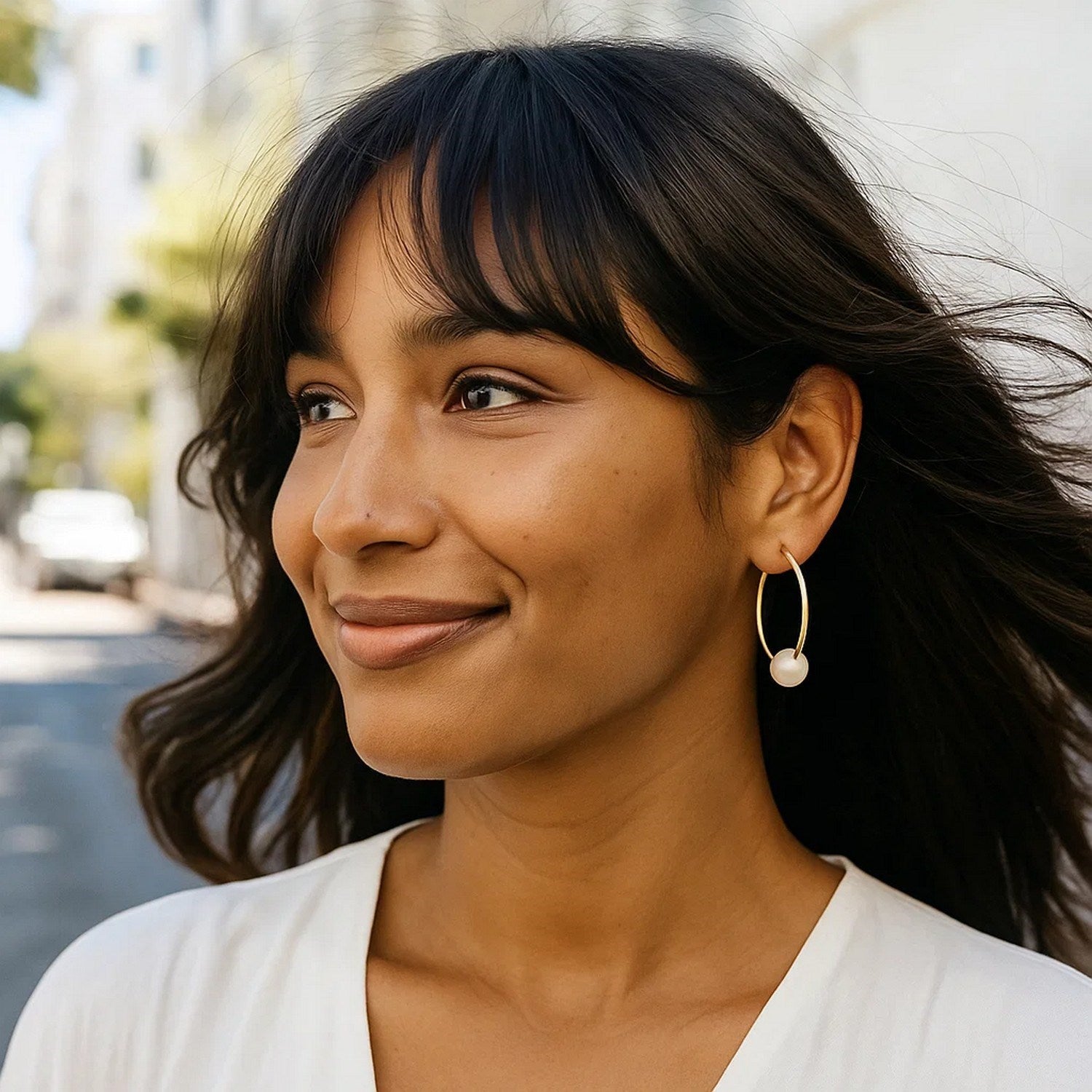 14k yellow gold round endless pearl earring on a woman with dark hair.