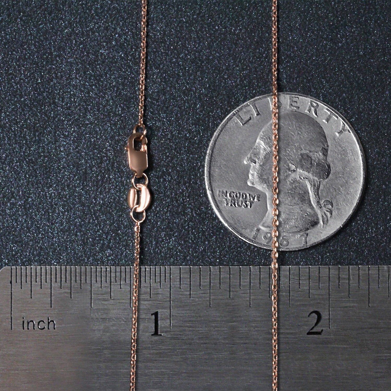 A rose gold diamond-cut cable link chain with a lobster clasp, shown next to a ruler and a quarter.