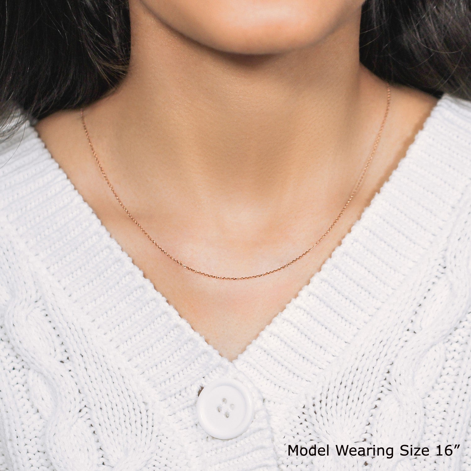 A rose gold diamond cut cable link chain on a model wearing a white sweater.