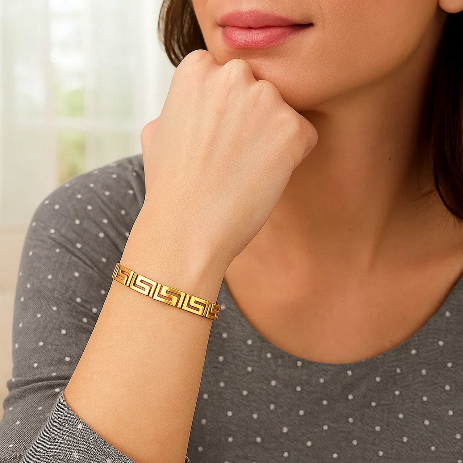 14k yellow gold Greek Key motif bracelet on a woman's wrist.