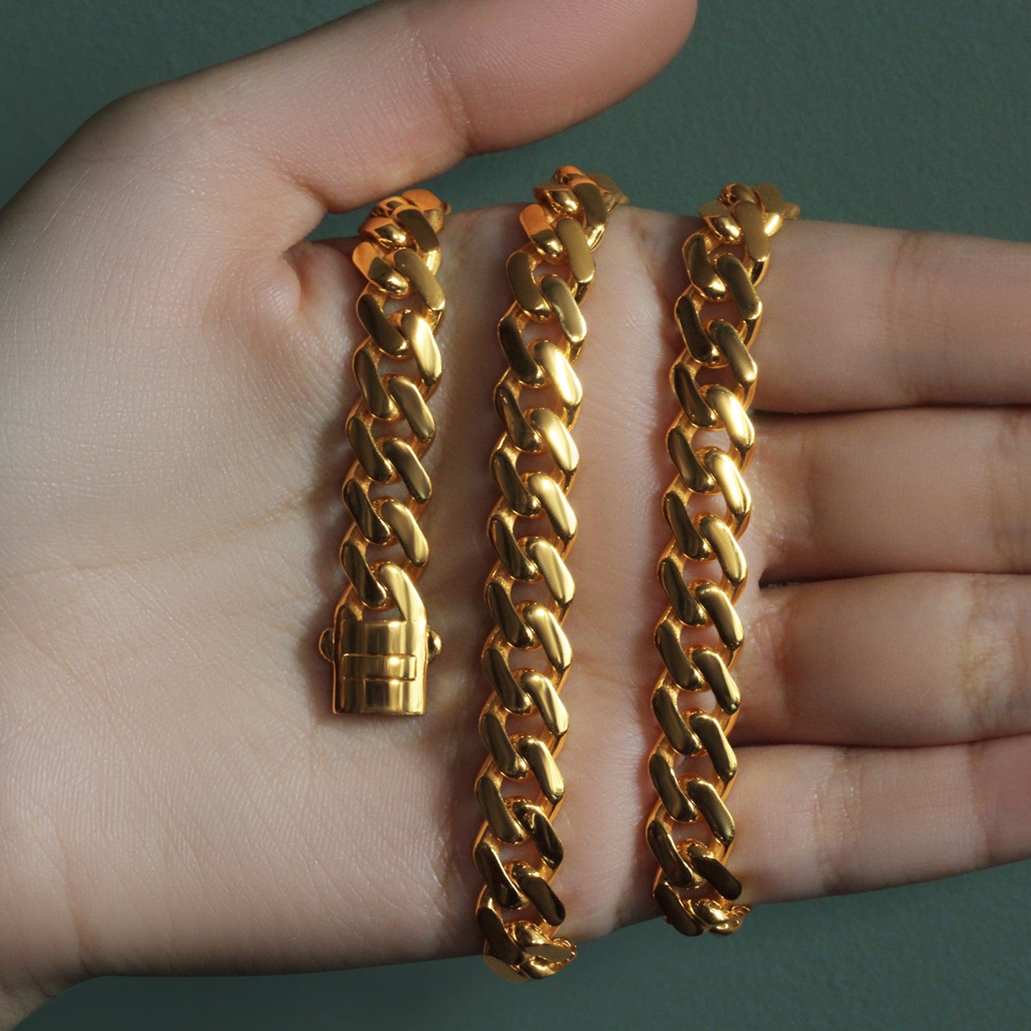 14k yellow gold polished curb chain necklace with a box clasp, held in a hand.