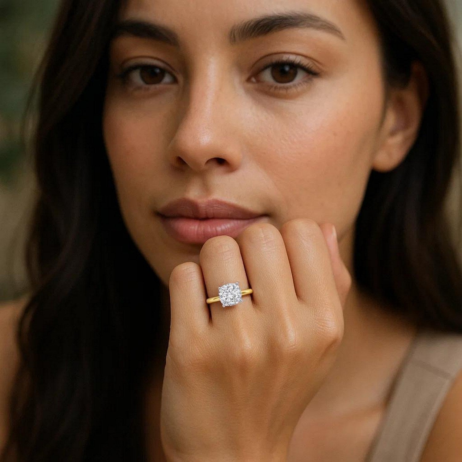 A woman wears a 1.50 carat cushion lab grown diamond ring in 14K yellow gold.