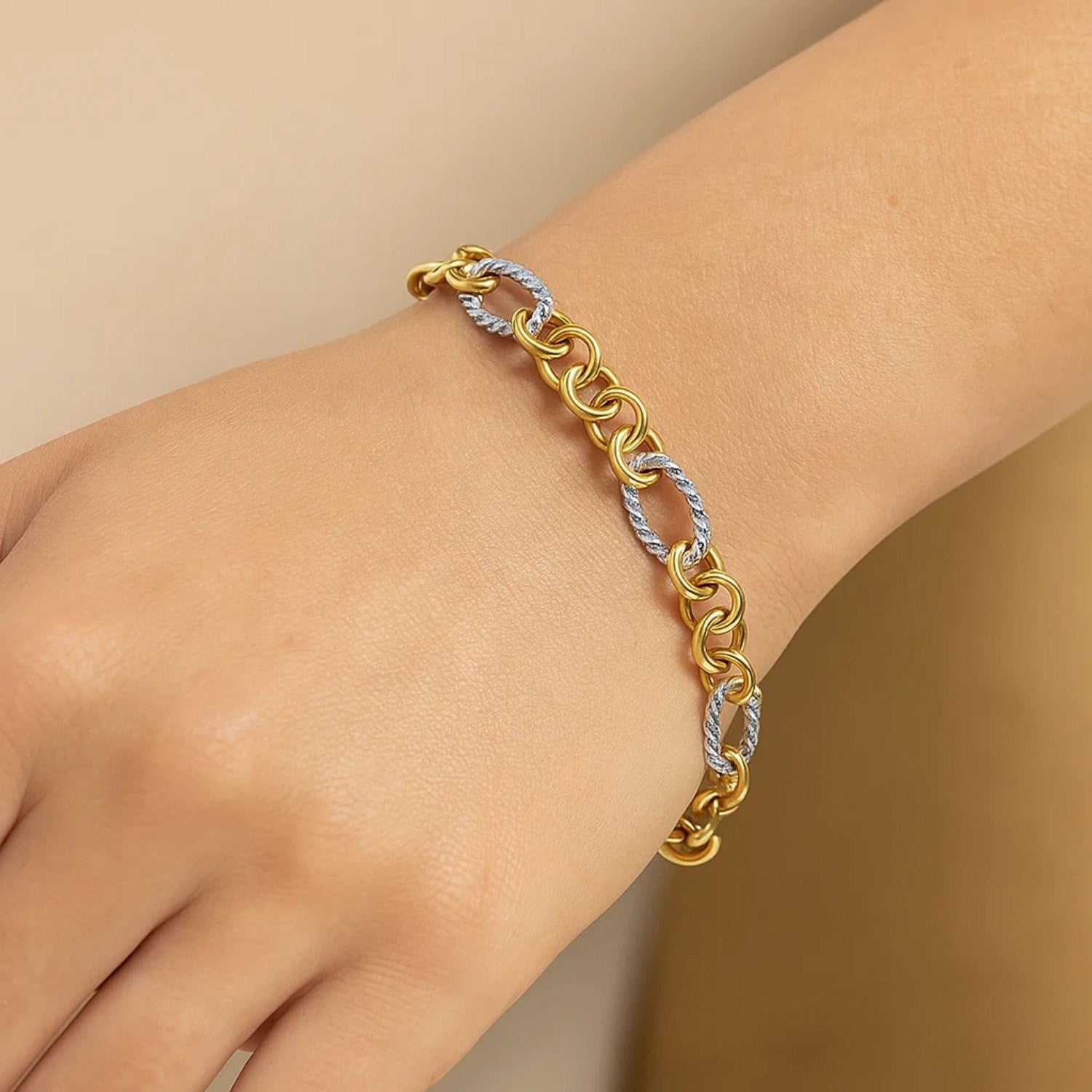 A two-tone gold bracelet with alternating smooth round and textured oval links.