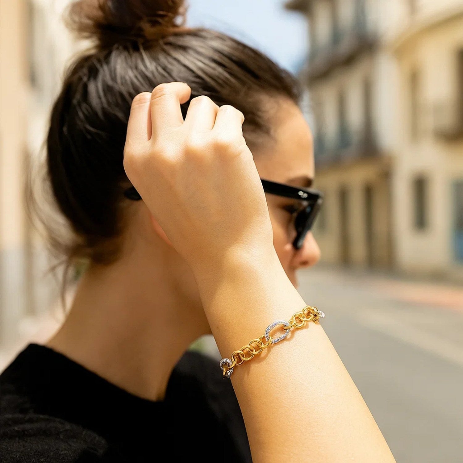 14k two-tone gold rope motif oval and round link chain bracelet on a woman's arm.