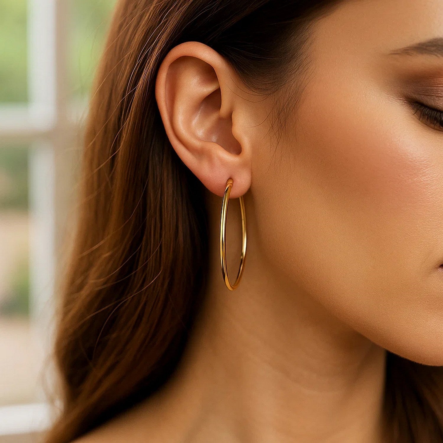 A woman wears a single 14K yellow gold endless hoop earring.