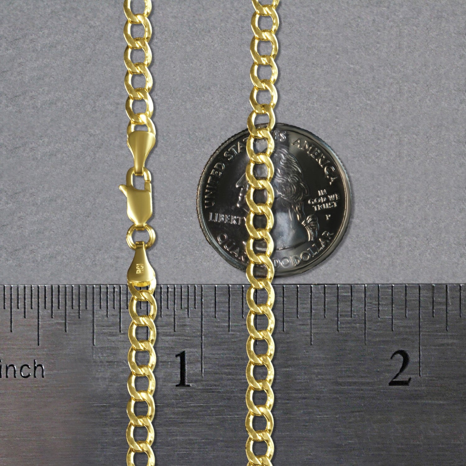A 10k yellow gold curb chain with a lobster clasp, shown next to a ruler and a quarter for scale.