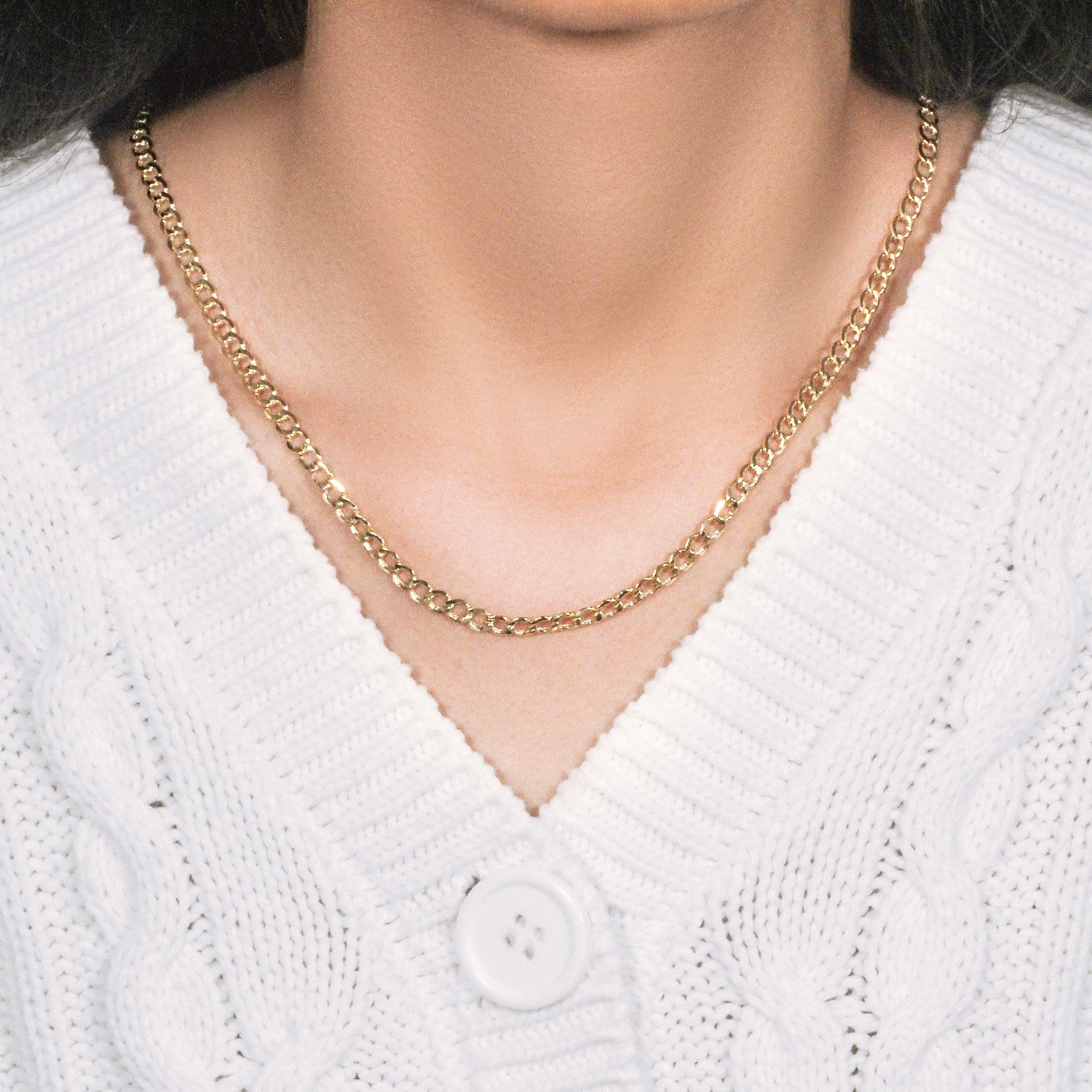 A 10k yellow gold curb chain with a lobster clasp on a person's neck.