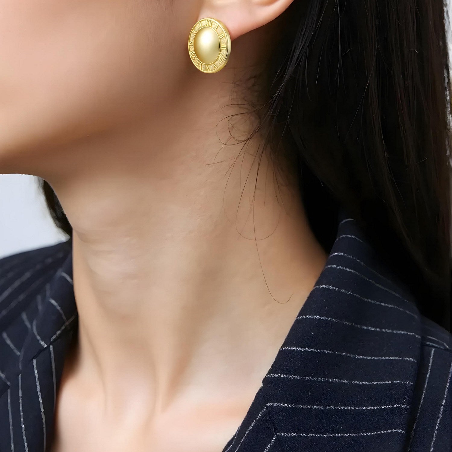 14K yellow gold Roman numeral button stud earrings on a woman's ear.