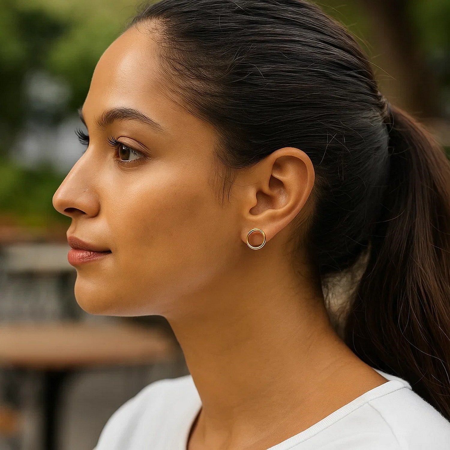 14k yellow gold open circle post earrings on a woman's ear.