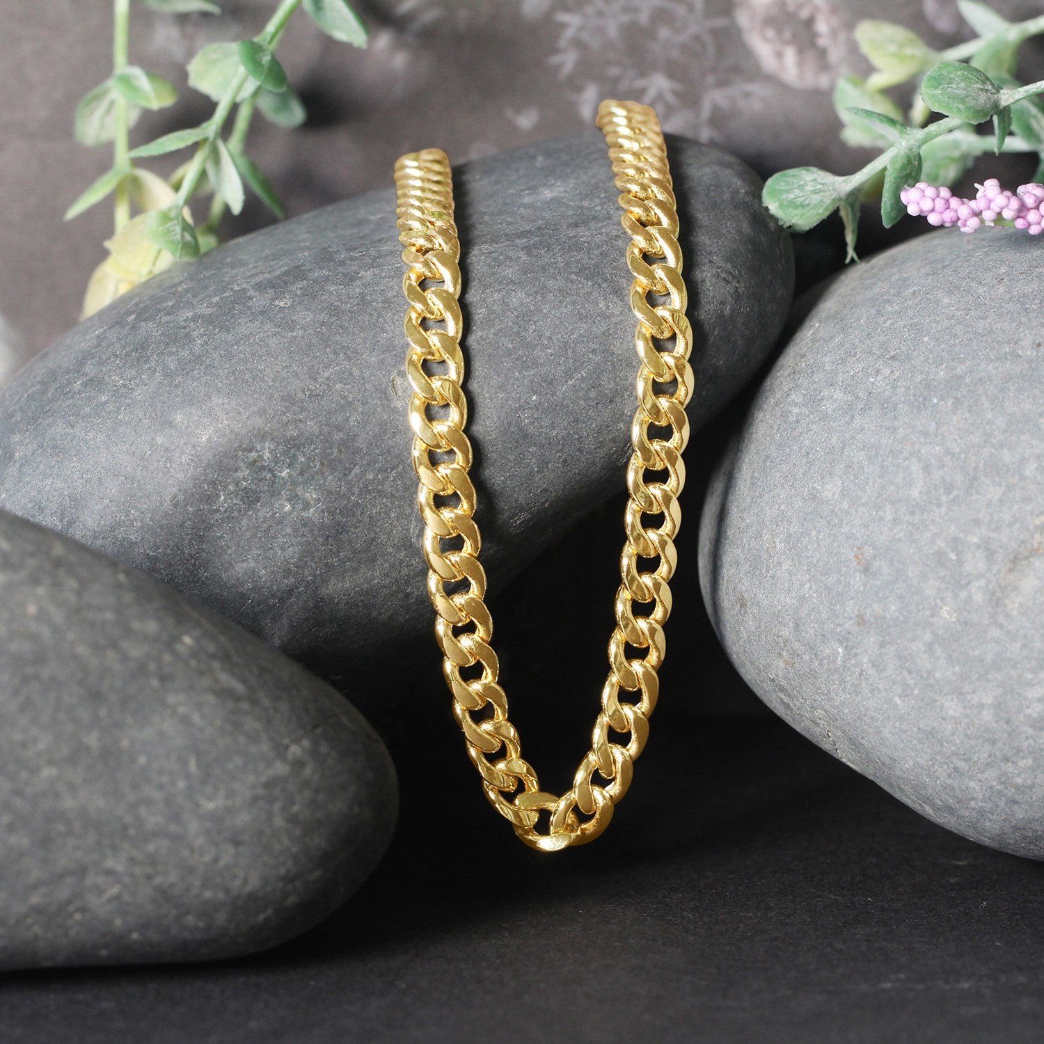 14k yellow gold Miami Cuban semi-solid chain, 5.50 mm wide, displayed on dark rocks.
