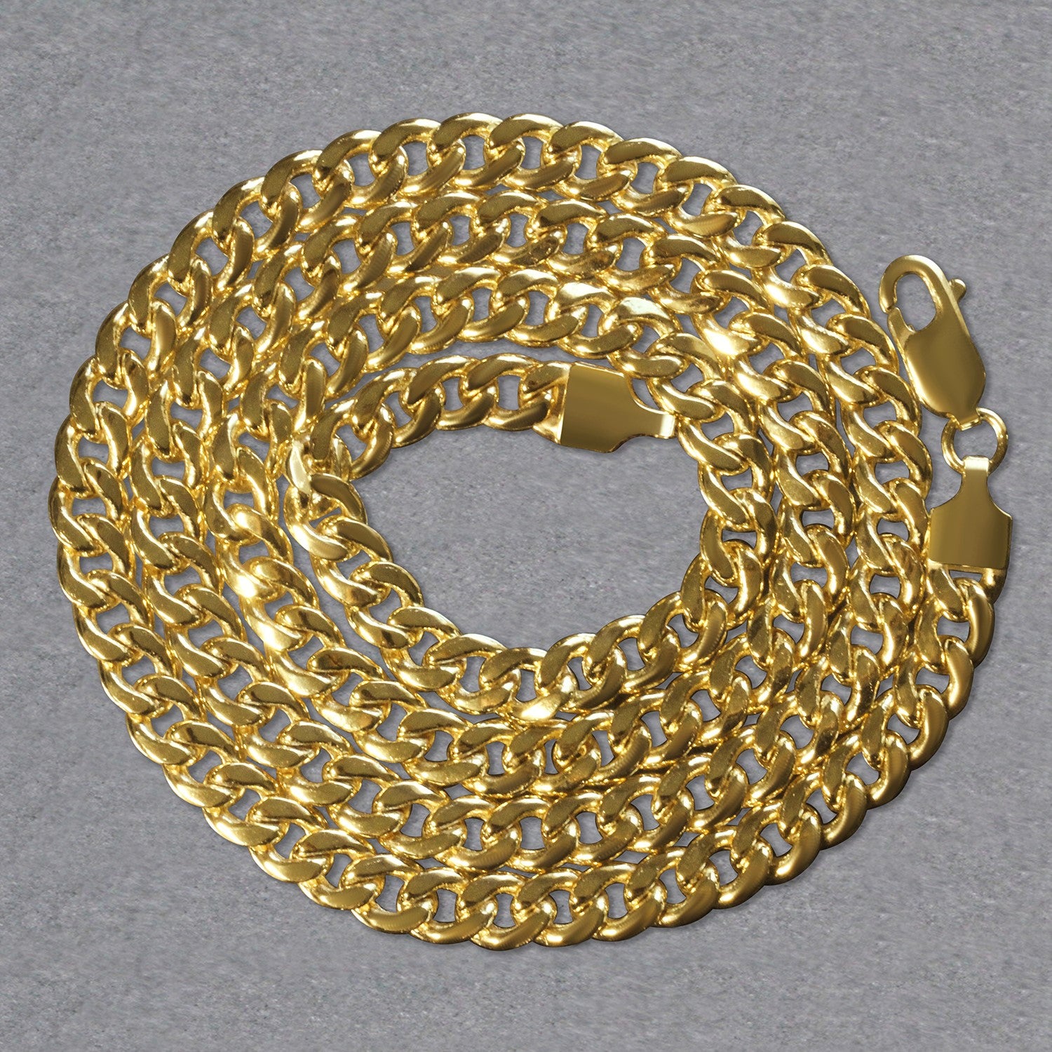 A 14k yellow gold Miami Cuban semi-solid chain, 5.50 mm wide, coiled on a gray surface.