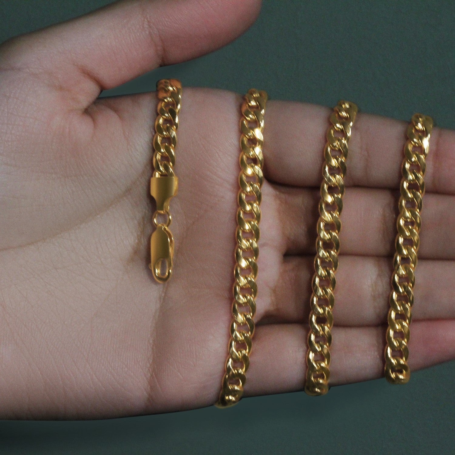 14k yellow gold Miami Cuban semi-solid chain with a lobster clasp, held in a hand.
