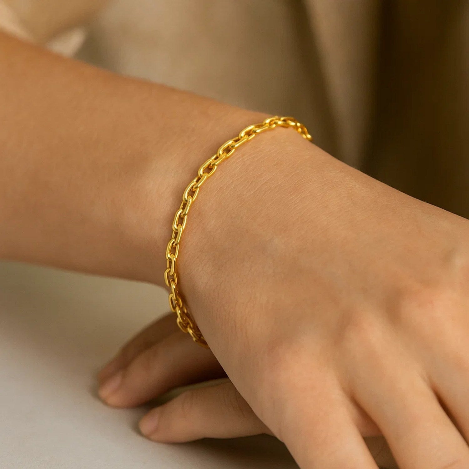A 14K yellow gold cable chain bracelet is worn on a person's wrist.
