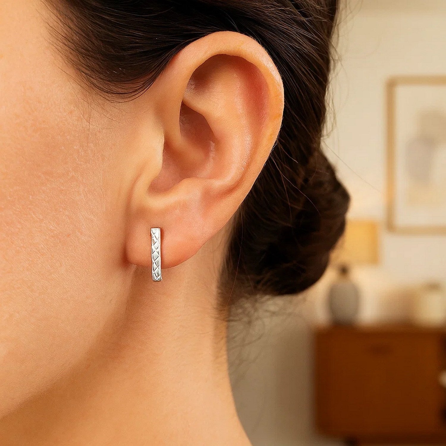 14k white gold textured bar earrings on a woman's ear.