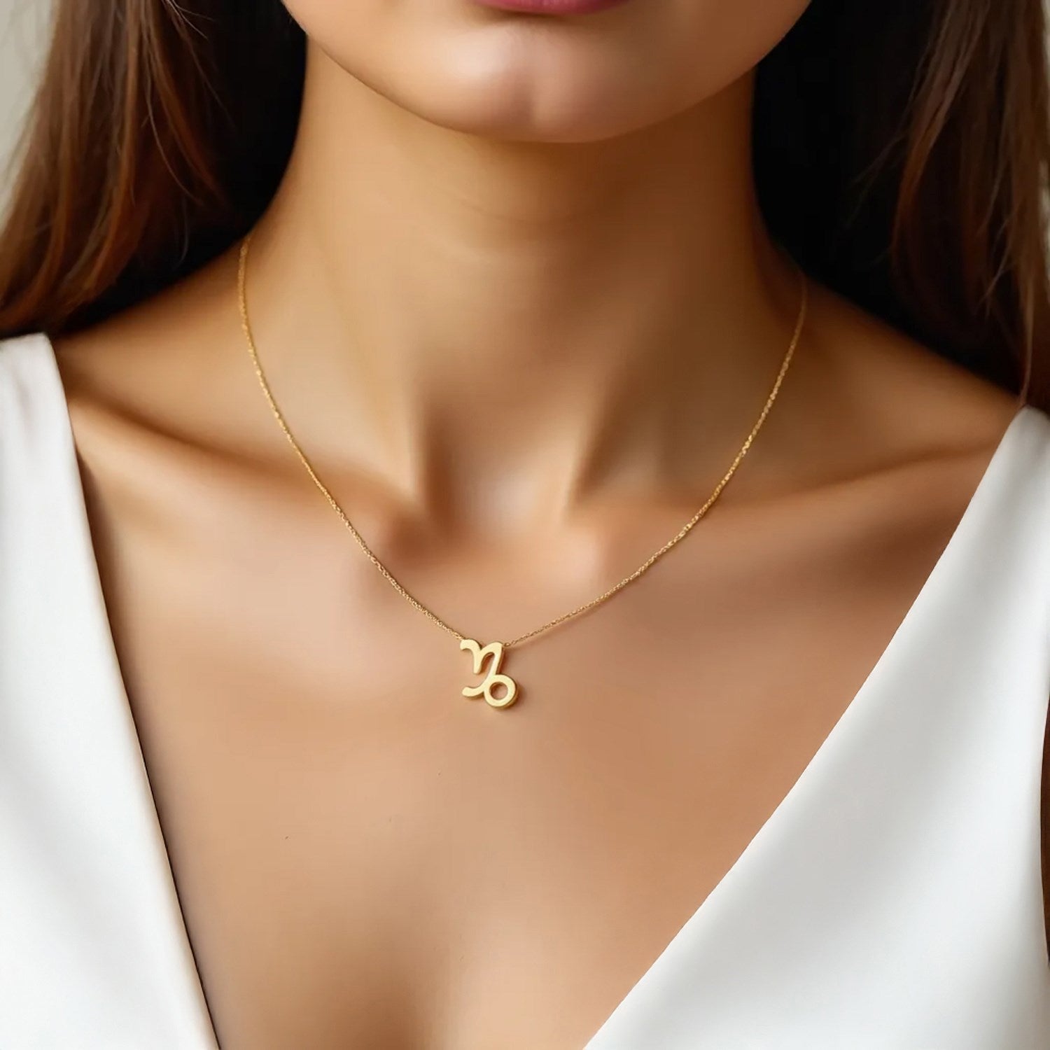 A 14K yellow gold Capricorn necklace on a woman's neck.