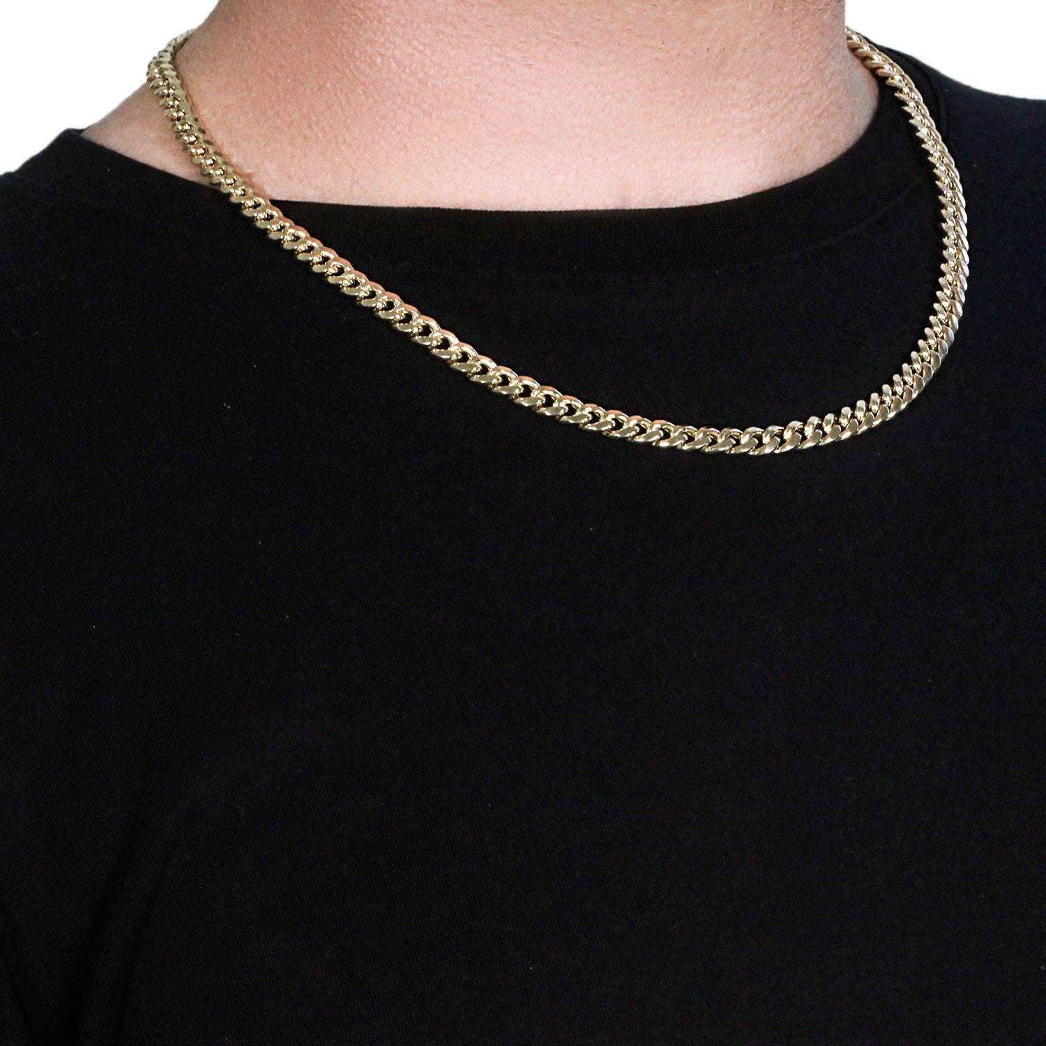 A 14k yellow gold semi-solid Miami Cuban chain, 6.60 mm wide, worn around a neck.