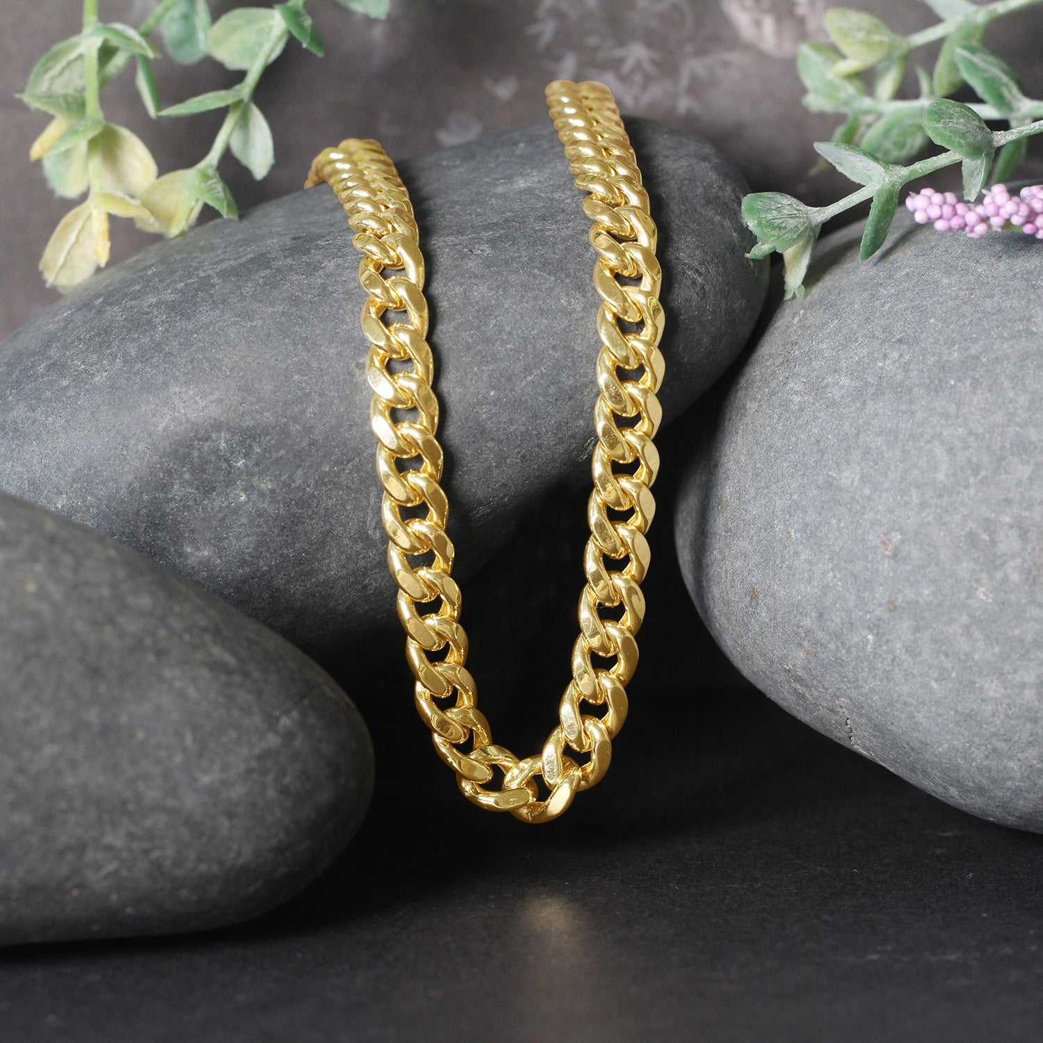 14k yellow gold semi-solid Miami Cuban chain, 6.60 mm wide, displayed on dark rocks.