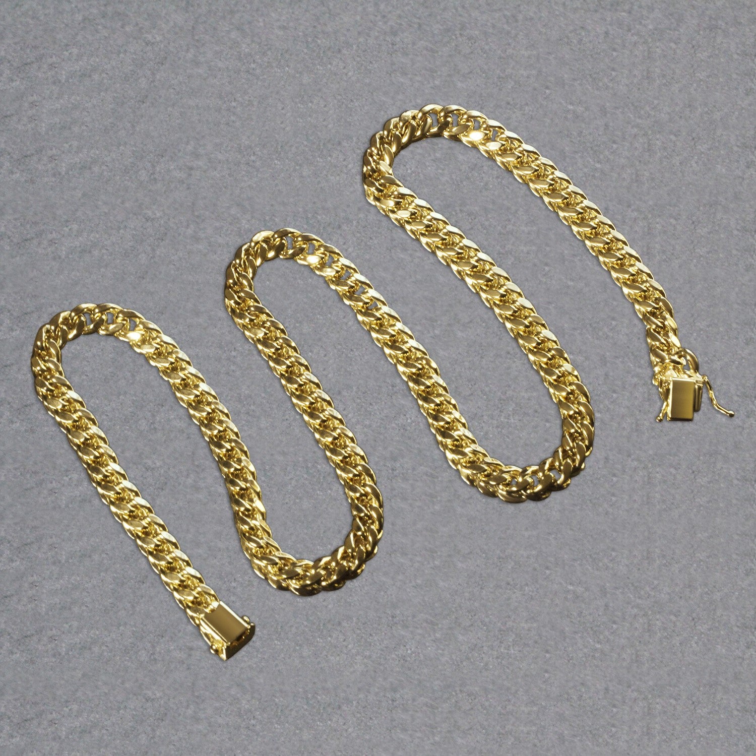 14k yellow gold semi-solid Miami Cuban chain with a box clasp on a gray surface.