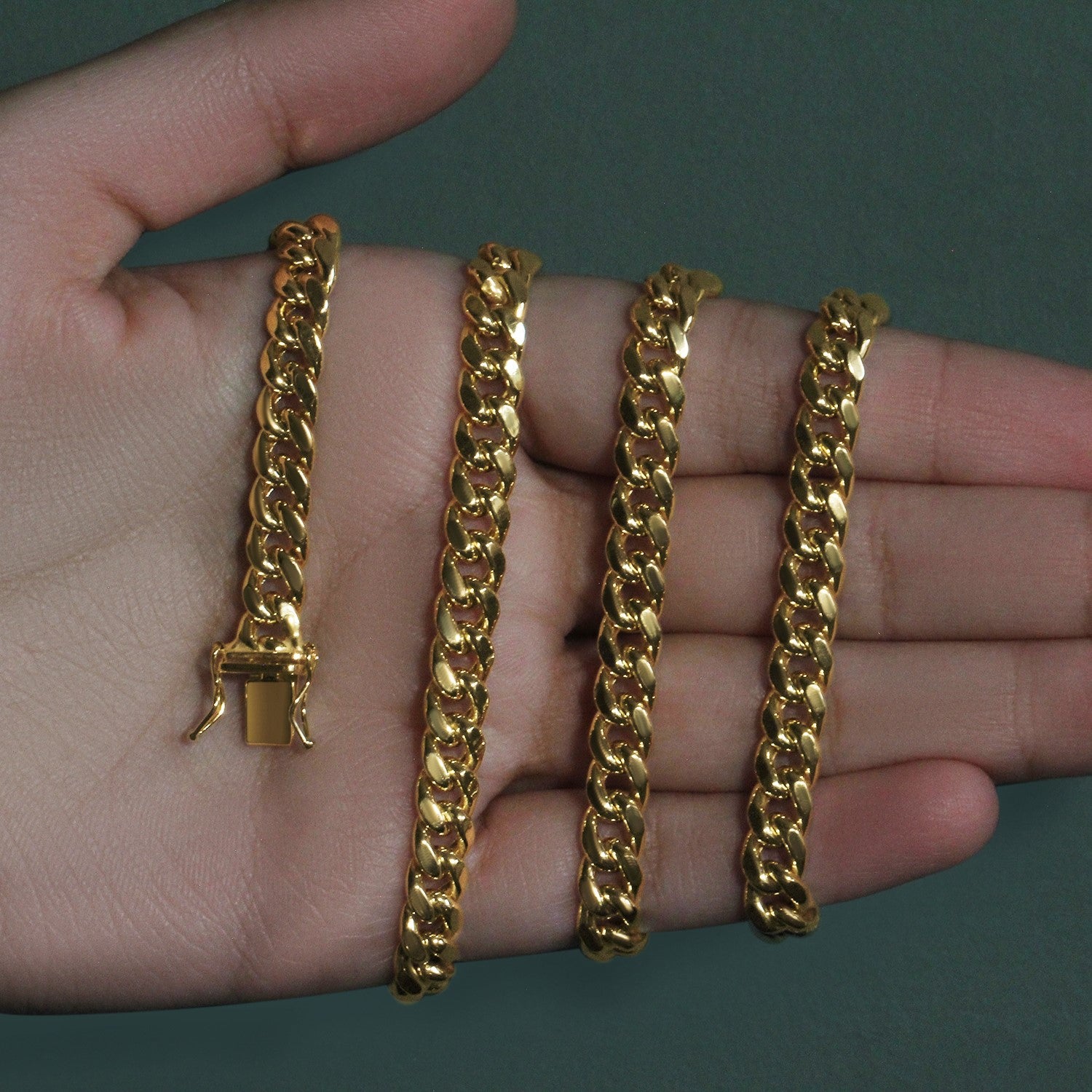 A 14k yellow gold semi-solid Miami Cuban chain with a box clasp is held in a hand.