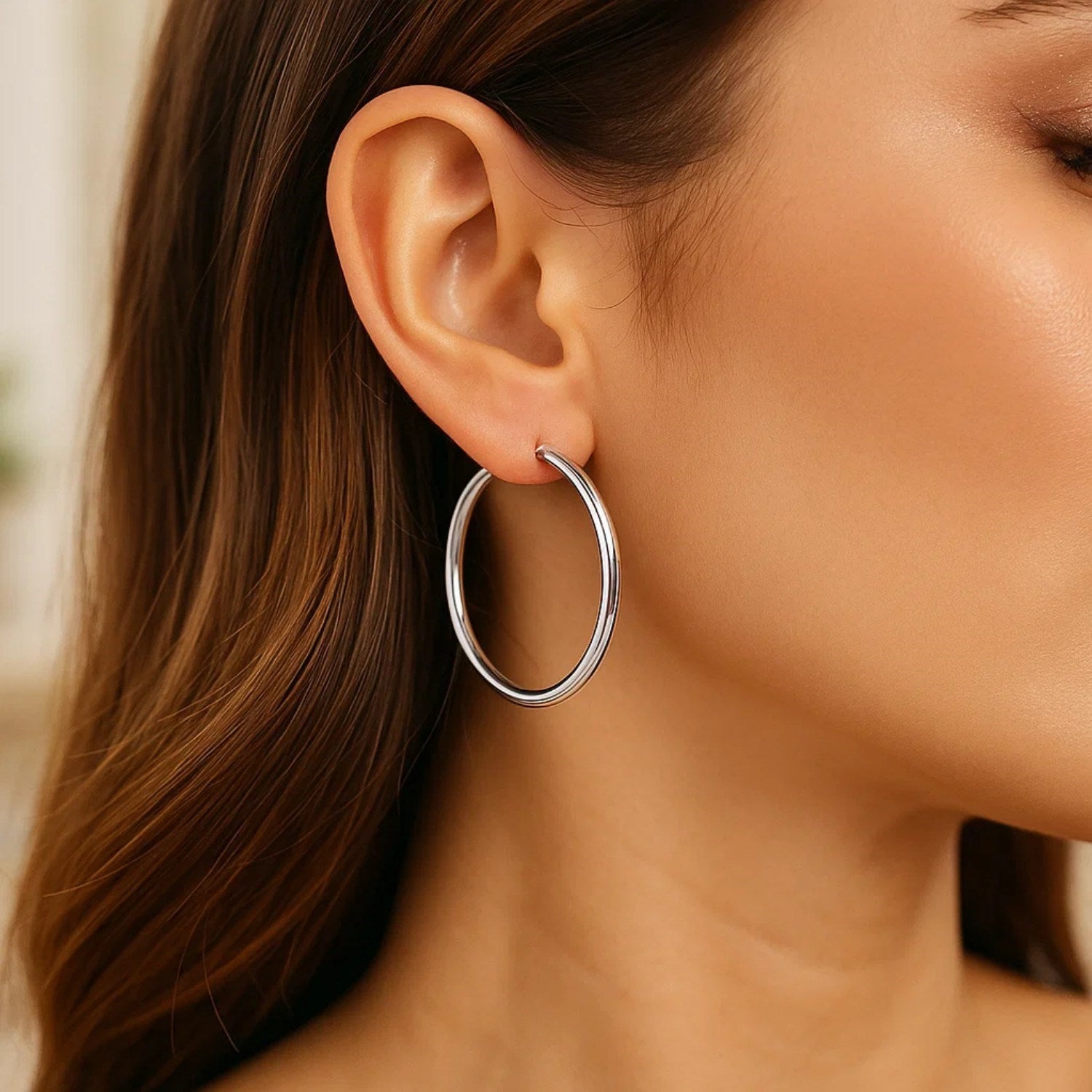 Sterling silver rhodium plated large polished classic hoop earrings on a model.