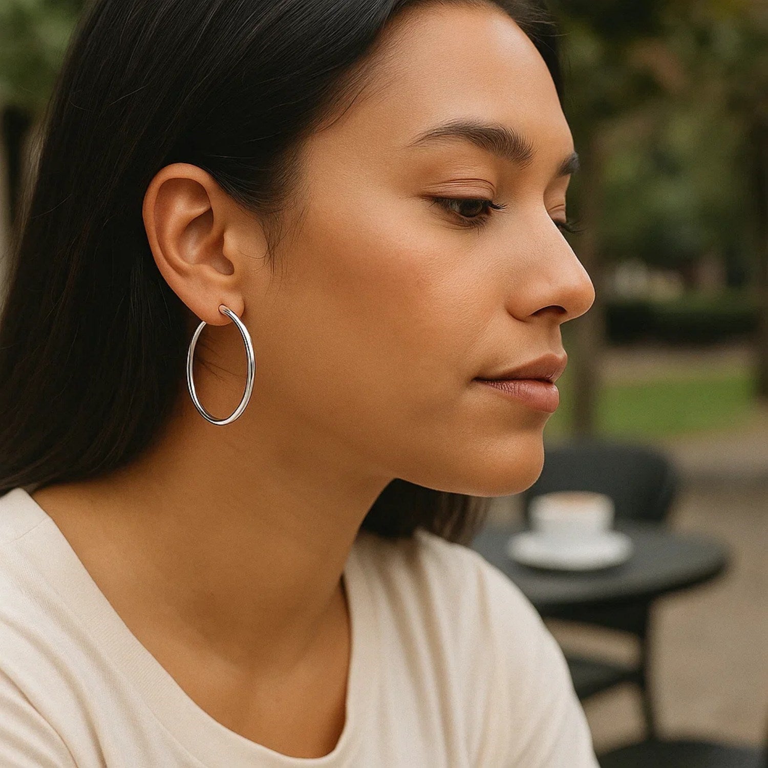 Sterling silver rhodium plated large polished classic hoop earrings on a woman.