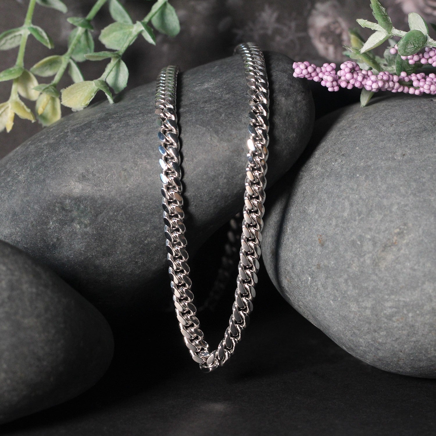 14k white gold classic Miami Cuban solid chain (5.00 mm) draped over dark rocks.