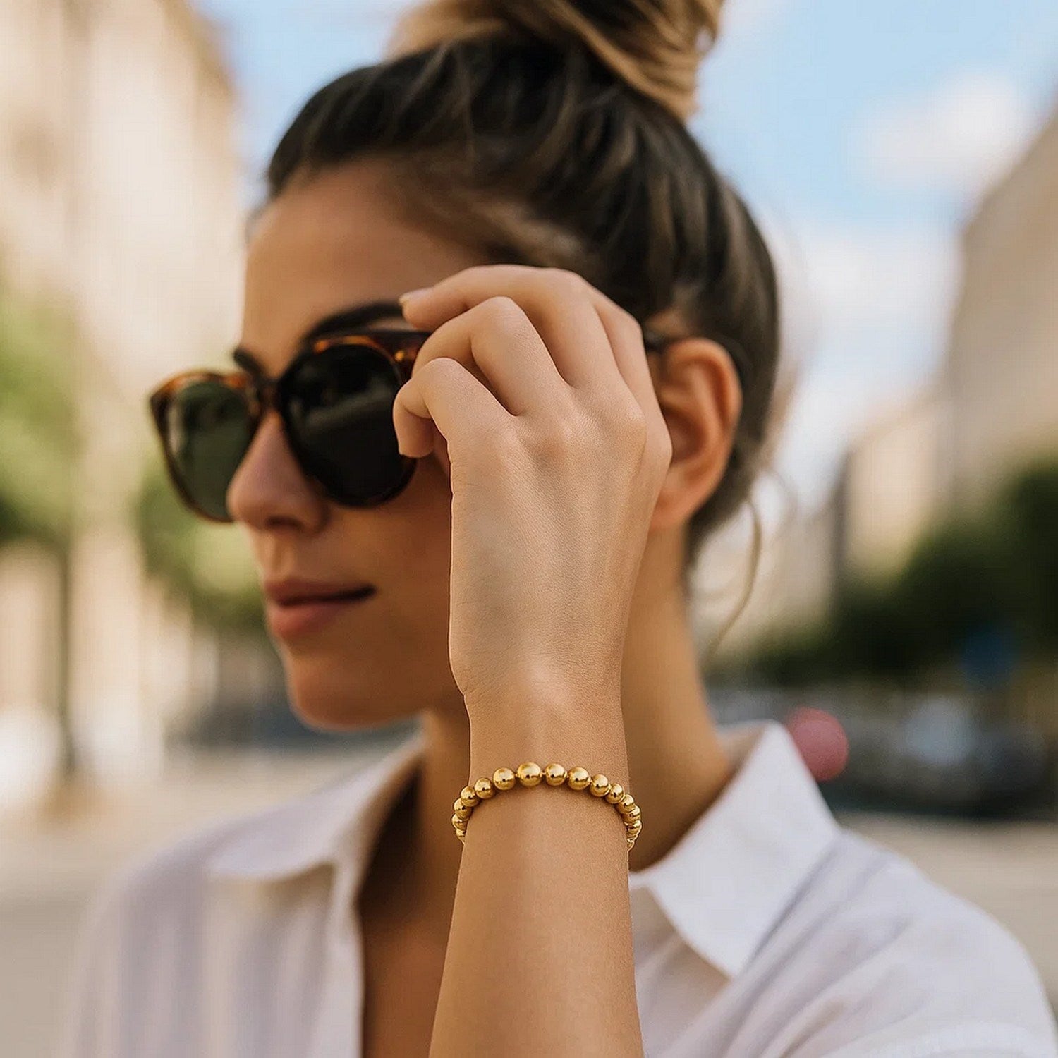 A woman wears a polished 14K yellow gold bead bracelet on her left wrist.